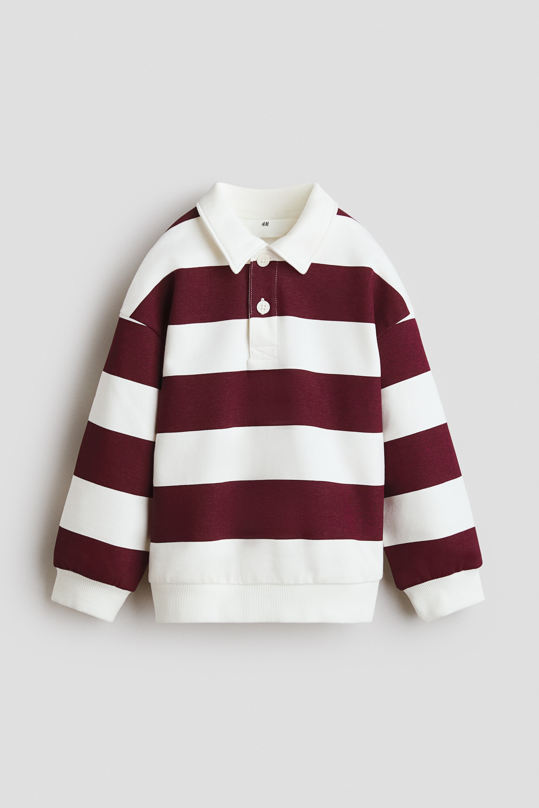 View larger image: The long-sleeved rugby shirt features horizontal stripes in maroon and cream, viewed from the front. It is crafted with a cream-coloured pointed collar, a two-button placket with white buttons, and ribbed cuffs and hem.