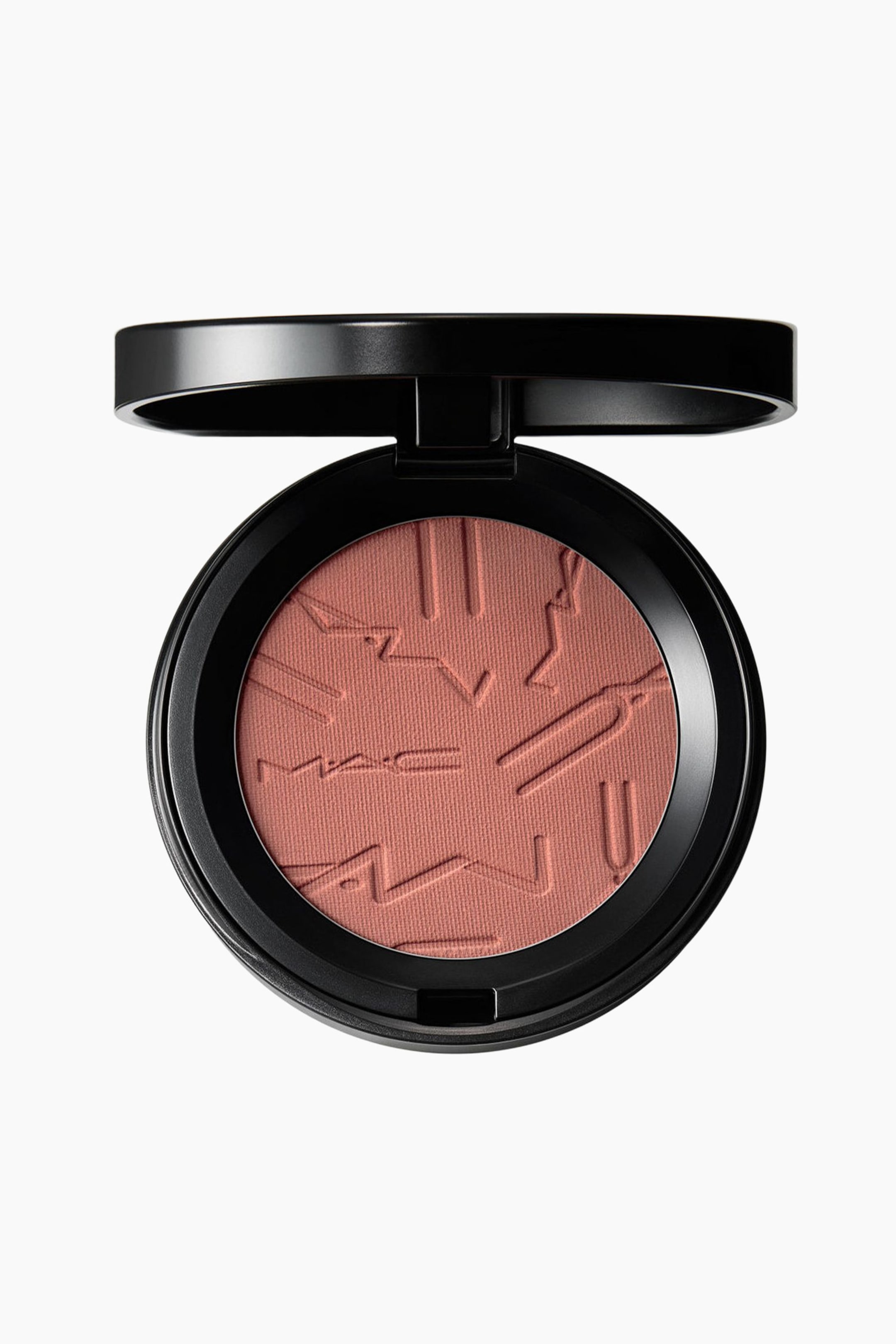 Visa större bild: En rund, svart sminkkompakt visas med locket öppet och vinklat bakåt. Inuti finns ett persikofärgat rosa puder med en präglad design av stiliserade bokstäver, inklusive "MAC"-logotypen, på ytan.