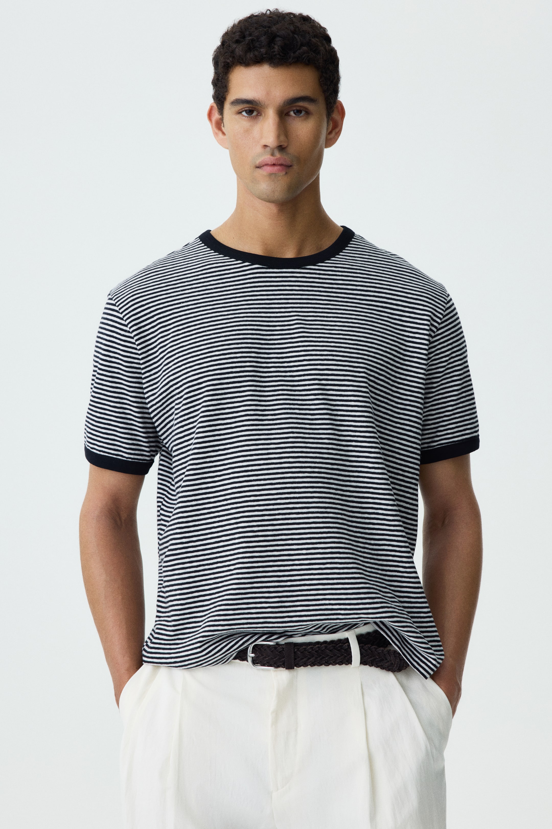 Visa större bild: En svartvit randig t-shirt bärs, med horisontella ränder, svarta kortärmade muddar och en svart rund hals. Den är vänd framåt och visar sin vanliga passform.