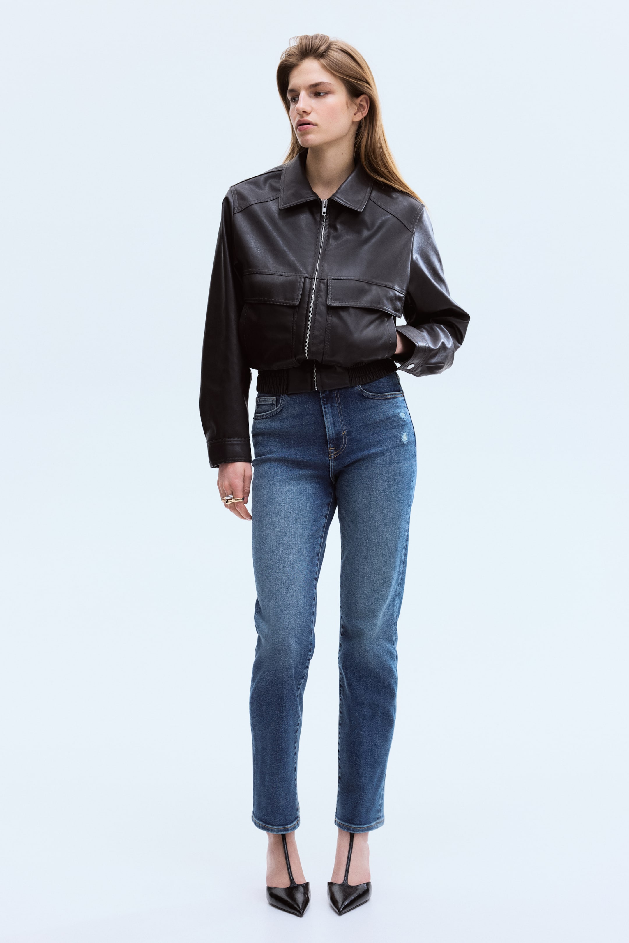 View larger image: The black leather-look bomber jacket features a pointed collar, a full-zip front, and two flap chest pockets, while showcasing long sleeves with elasticated cuffs and a cropped elasticated hem.