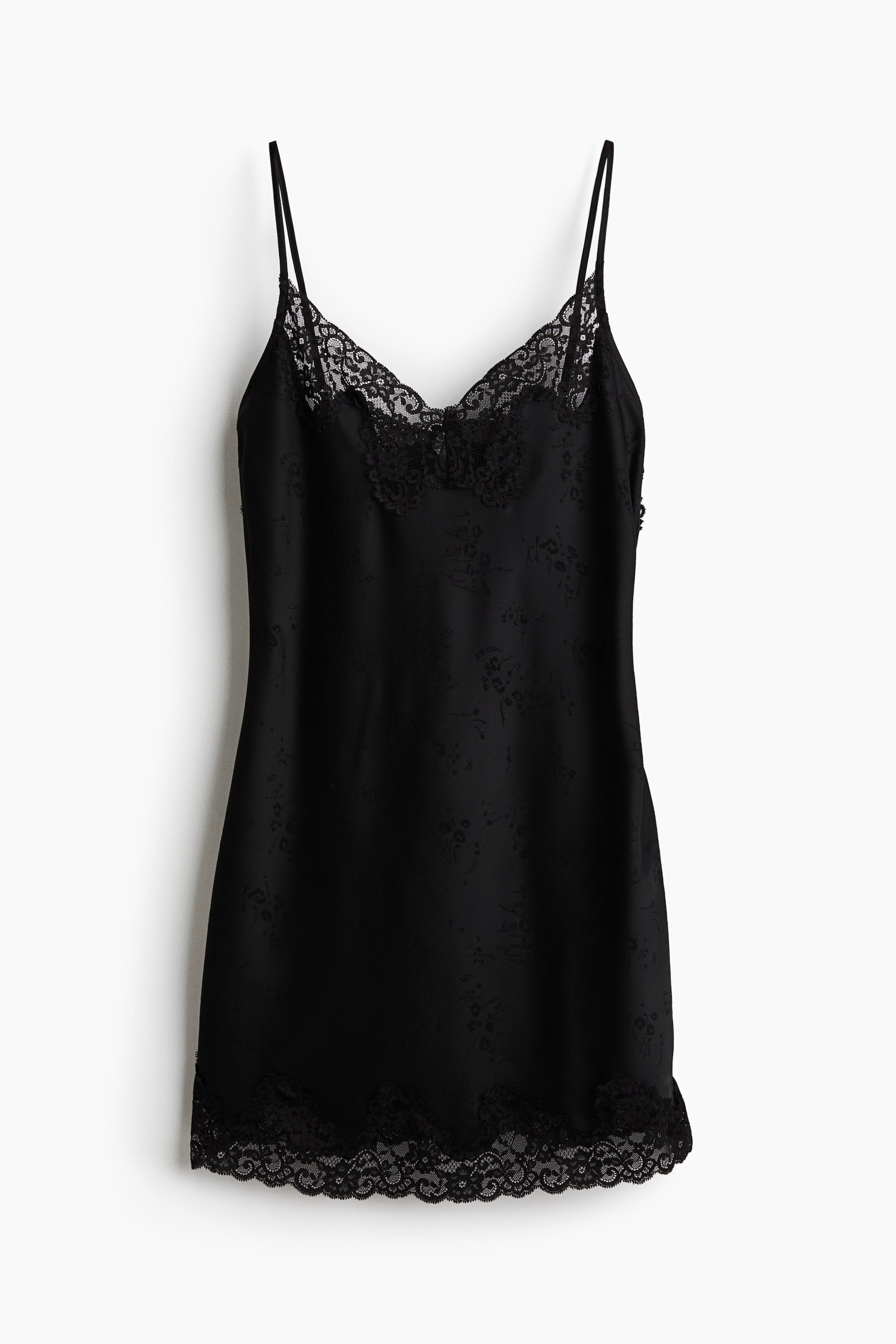 Προβολή μεγαλύτερης εικόνας: Ένα μαύρο slip dress κρέμεται σε μπροστινή όψη, με διακριτικό τονικό floral jacquard μοτίβο σε όλη την επιφάνειά του. Το σχέδιο περιλαμβάνει λεπτές τιράντες spaghetti, λαιμόκοψη V με λεπτομέρειες από φίνα μαύρη δαντέλα και αντίστοιχο κυματιστό τελείωμα από δαντέλα στο στρίφωμα.