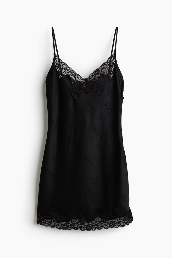 O rochie slip neagrÄ este prezentatÄ din faÈÄ, evidenÈiind un model floral jacquard tonal discret pe Ã®ntreaga suprafaÈÄ. Designul include bretele subÈiri spaghetti, un decolteu Ã®n V detaliat cu dantelÄ neagrÄ delicatÄ Èi o bordurÄ asortatÄ din dantelÄ festonatÄ de-a lungul tivului. - 1