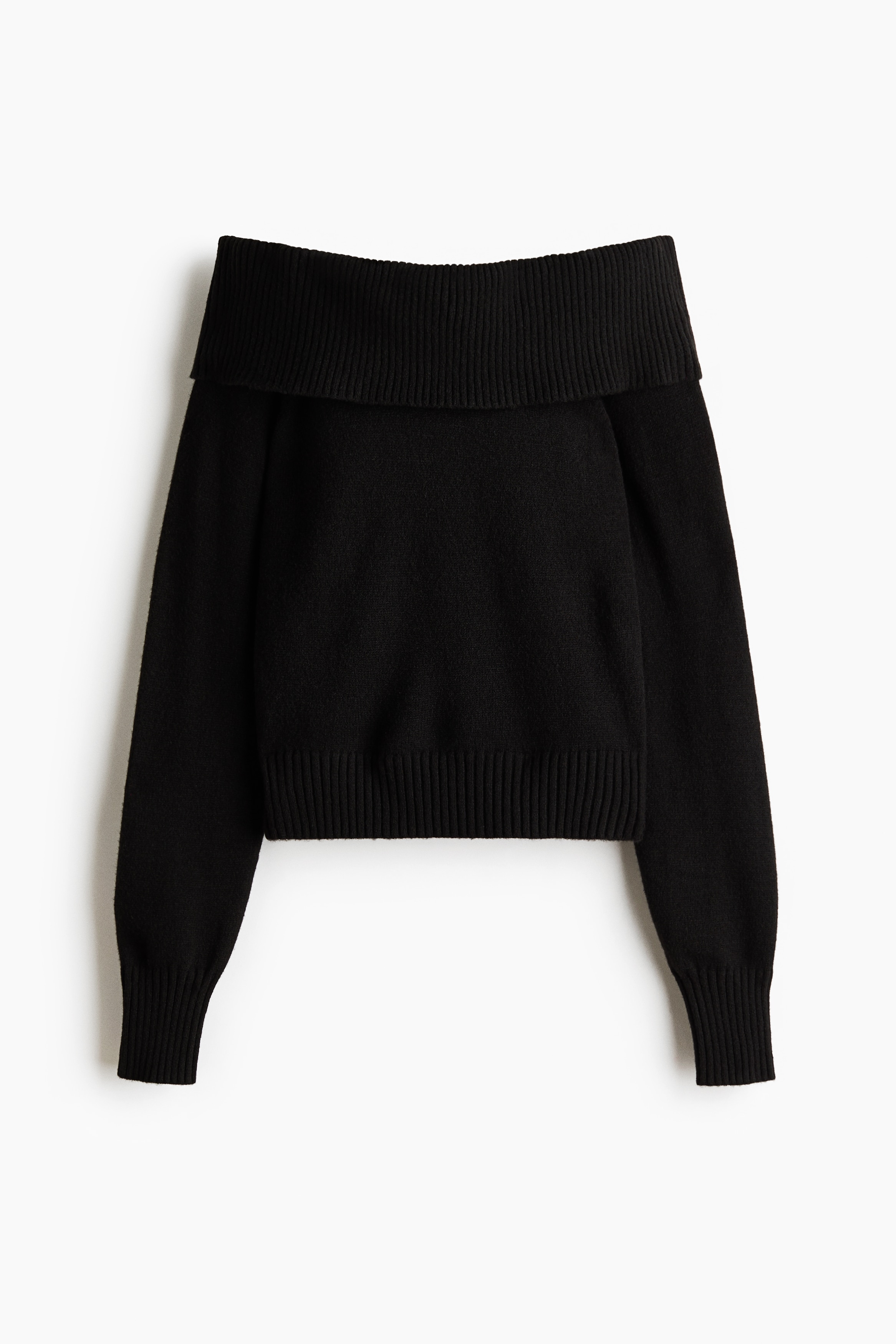 Het model draagt een zwarte sweater van zachte knit met een off-shoulder design. De sweater heeft een brede, geribbelde omgeslagen halslijn die nonchalant over Ã©Ã©n schouder valt, lange mouwen met geribbelde boorden en een geribbelde zoom.