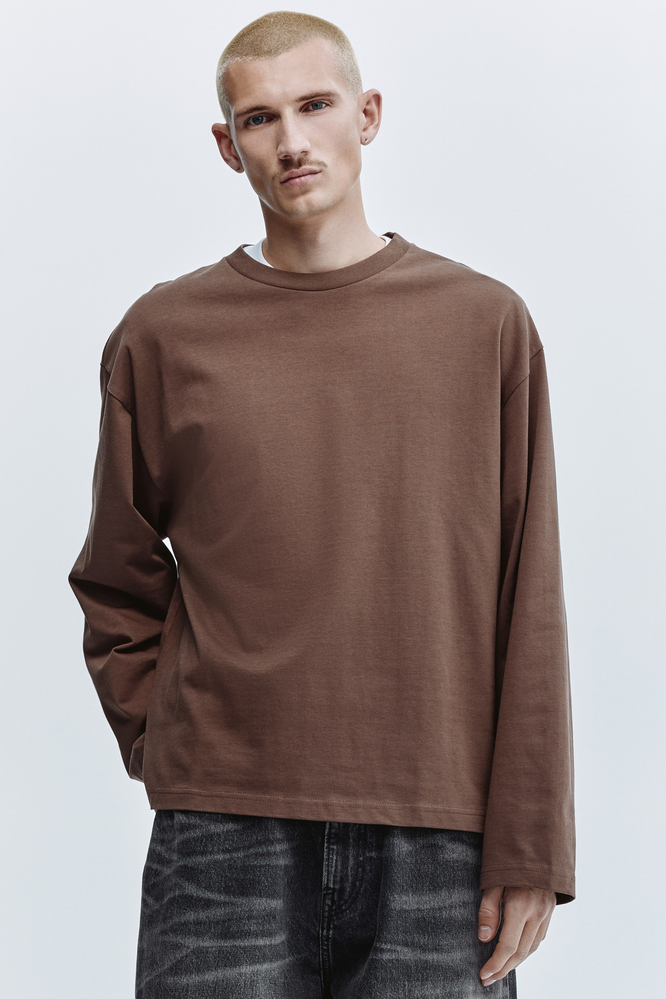 View larger image: A brown long-sleeved crew-neck top with a relaxed fit, featuring long, loose sleeves, a straight hem, and a white layer peeking out from the neckline.