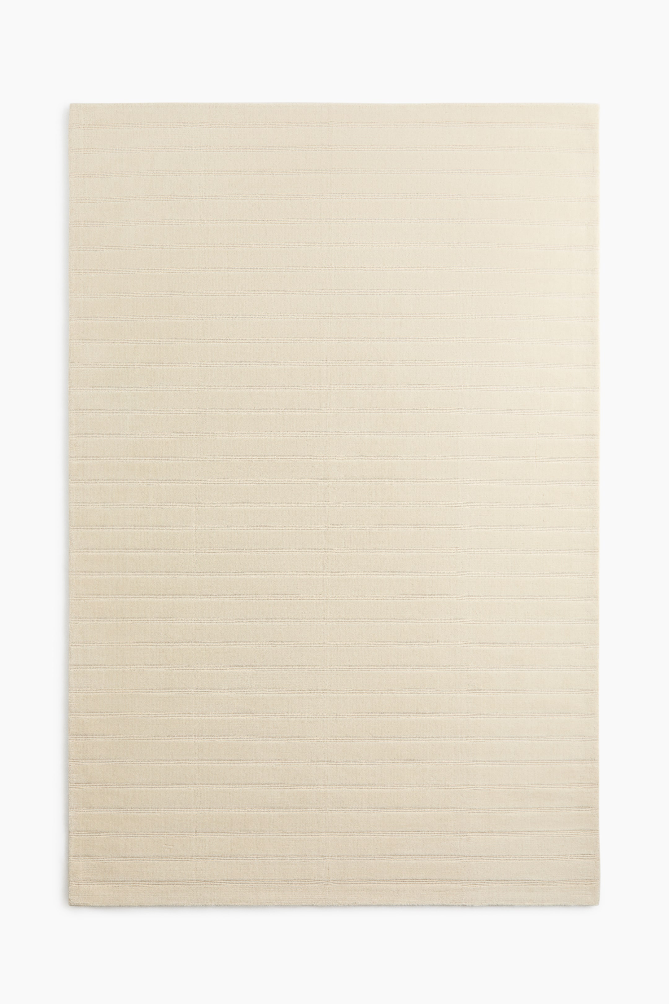 View larger image: A rectangular rug is laid flat, showcasing a light beige colour with a horizontal ribbed texture across its entire surface.