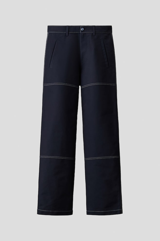 Dunkelmarineblaue Hose in lockerer Passform mit geradem Bein und markanten weiÃen KontrastnÃ¤hten entlang der NÃ¤hte, Knie und SÃ¤ume. Aus der Vorderansicht gezeigt, mit schrÃ¤gen Paspeltaschen an den Seiten, GÃ¼rtelschlaufen und einem Knopfverschluss am Bund. - 1
