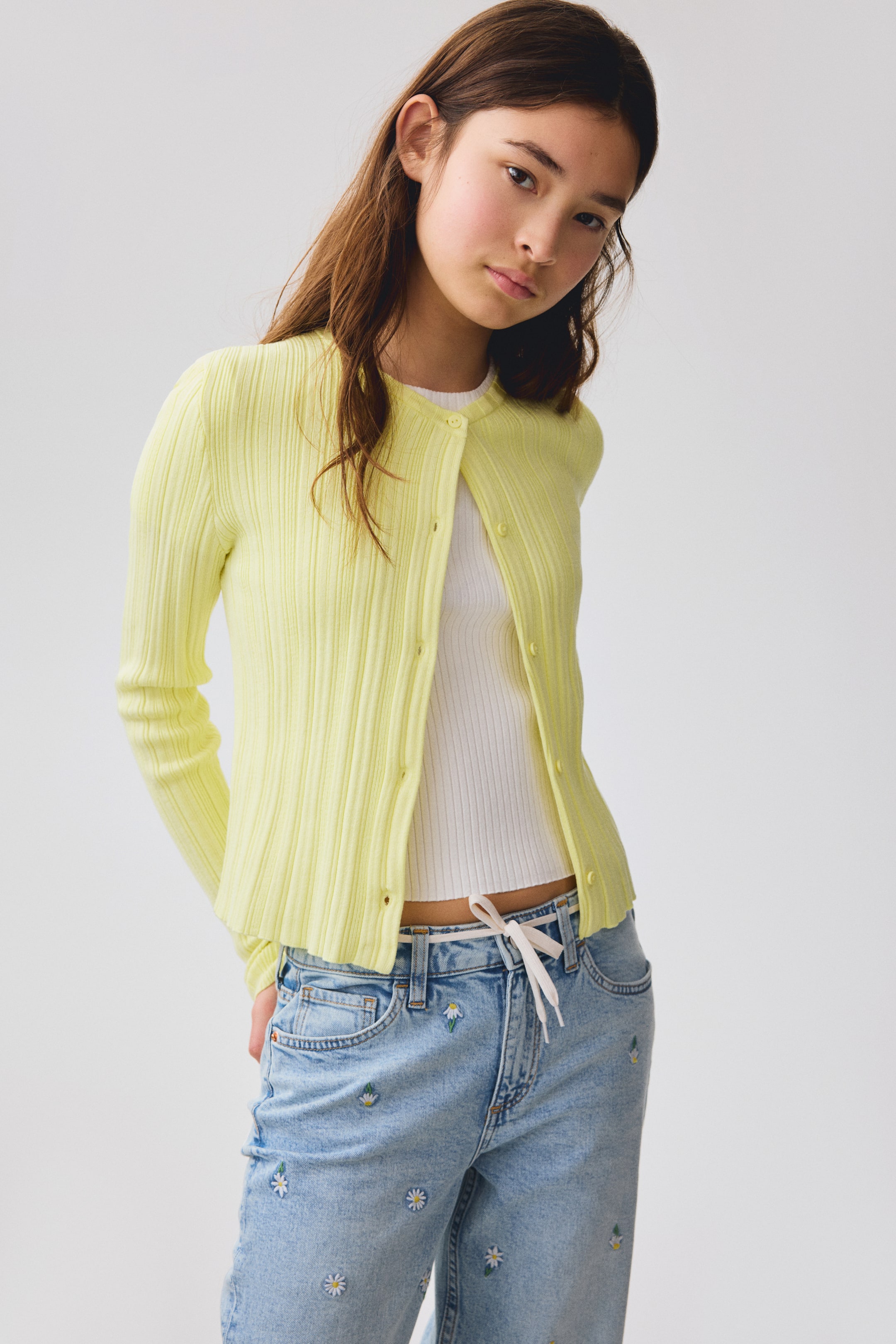 Agrandir l'image: Un cardigan jaune pâle présente une texture en maille fine et un col rond, vu de face. De petits boutons assortis descendent le long de son devant déboutonné, et il a des manches longues avec des bords finis proprement aux poignets et à l'ourlet.