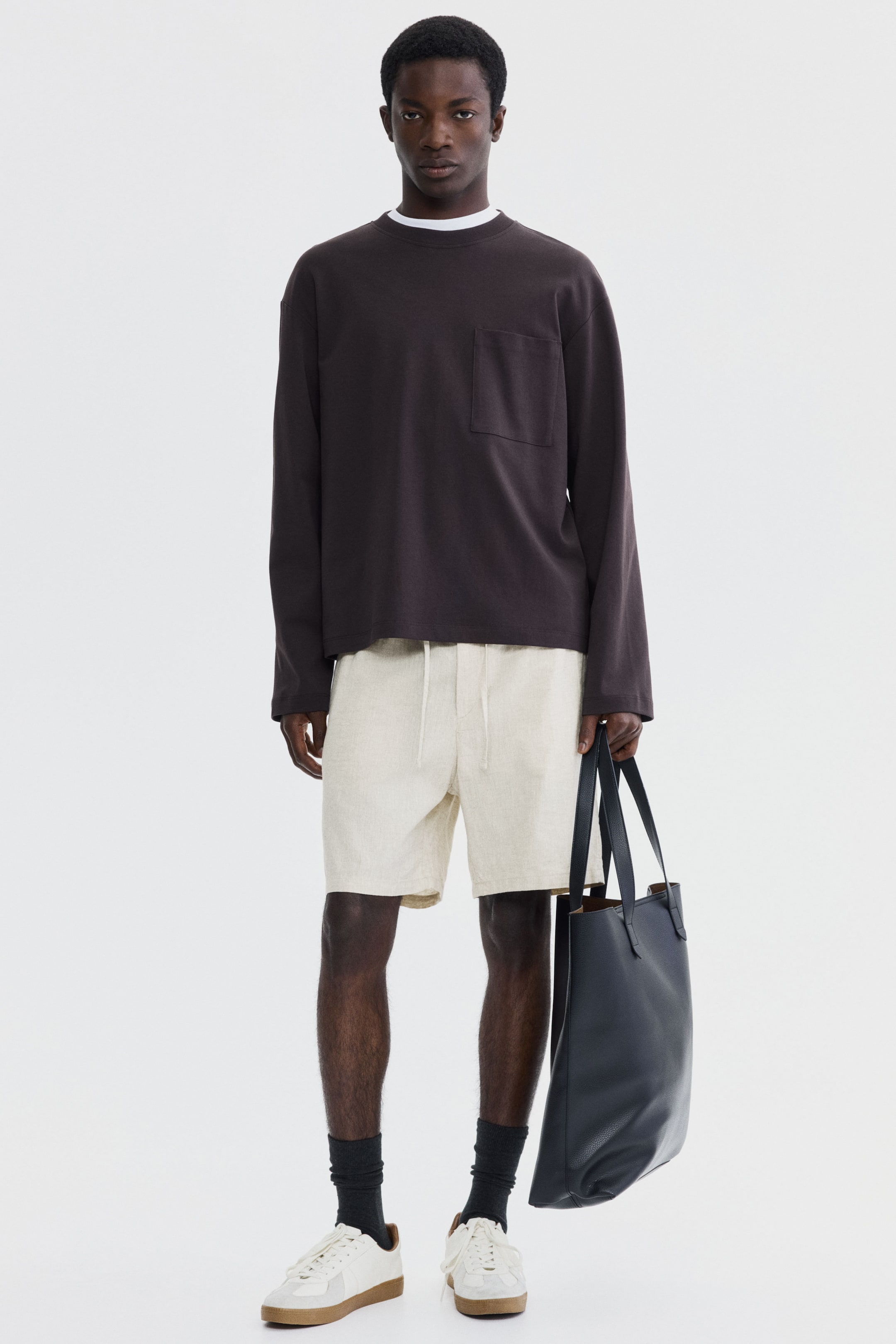 View larger image: "A dark brown long-sleeve shirt, featuring a crew neck and a single patch pocket on the left chest, is worn over a white t-shirt with its neckline visible. The shirt showcases a relaxed fit and is facing forward."