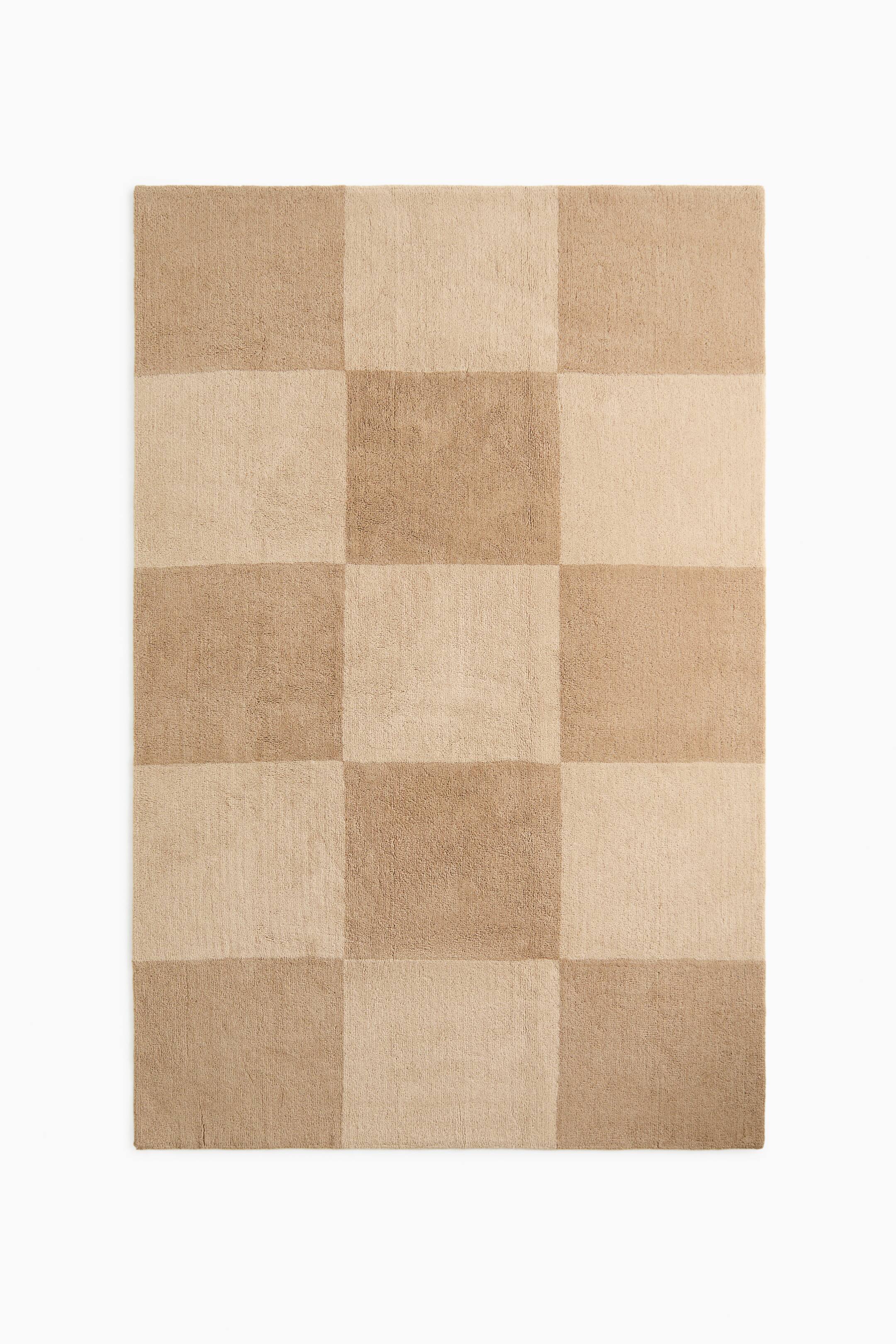 View larger image: A rectangular rug is lying flat, exhibiting a soft, woven texture with a chequered pattern of alternating light and medium beige squares.