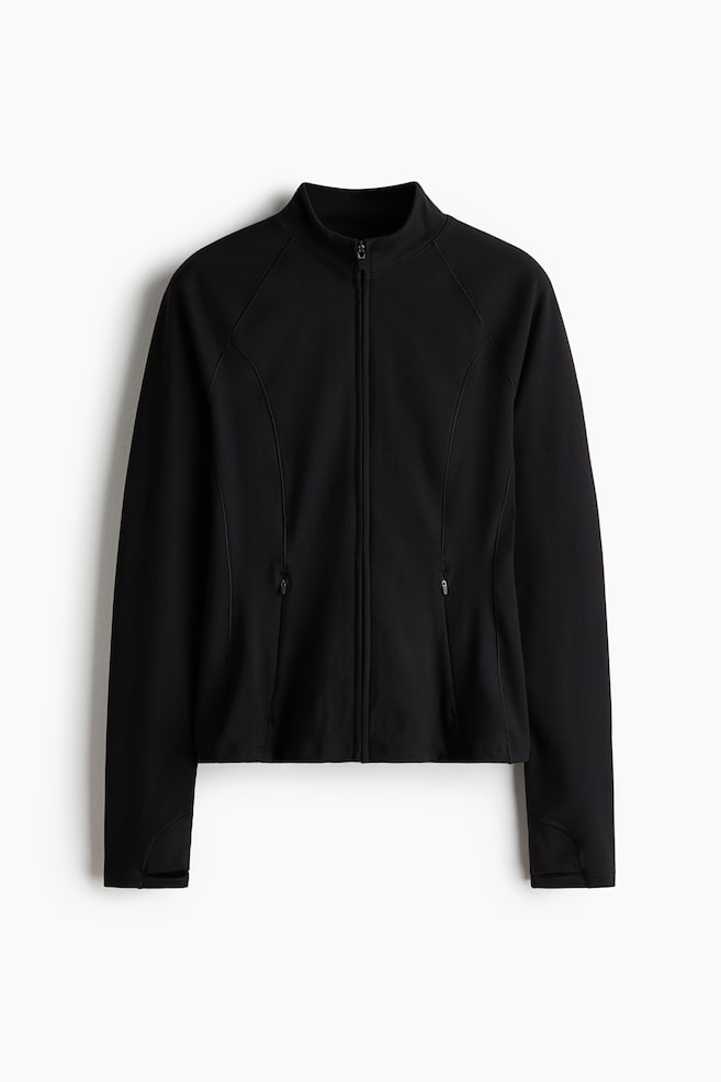 Eine schwarze Sportjacke ist von vorn zu sehen und verfÃ¼gt Ã¼ber einen Stehkragen, einen durchgehenden FrontreiÃverschluss und konturierte NÃ¤hte fÃ¼r eine figurbetonte Silhouette. Die Jacke zeigt lange RaglanÃ¤rmel mit DaumenlÃ¶chern an den ÃrmelbÃ¼ndchen sowie zwei Seitentaschen mit senkrechten ReiÃverschlussverschlÃ¼ssen. - 1