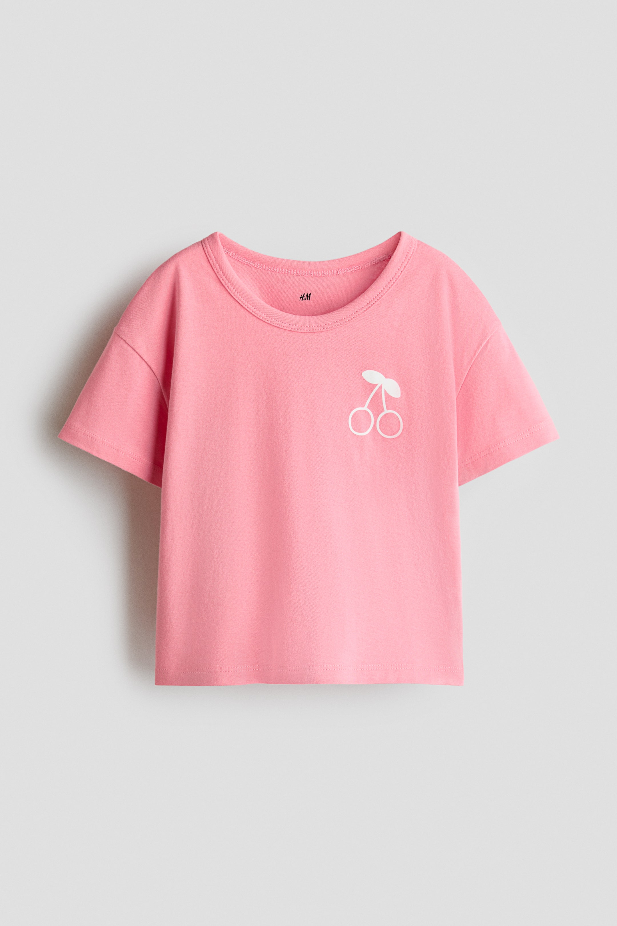 View larger image: A pink t-shirt is presenting its FRONT, featuring a round neckline and short sleeves. A white cherry design is embroidered on the left chest.