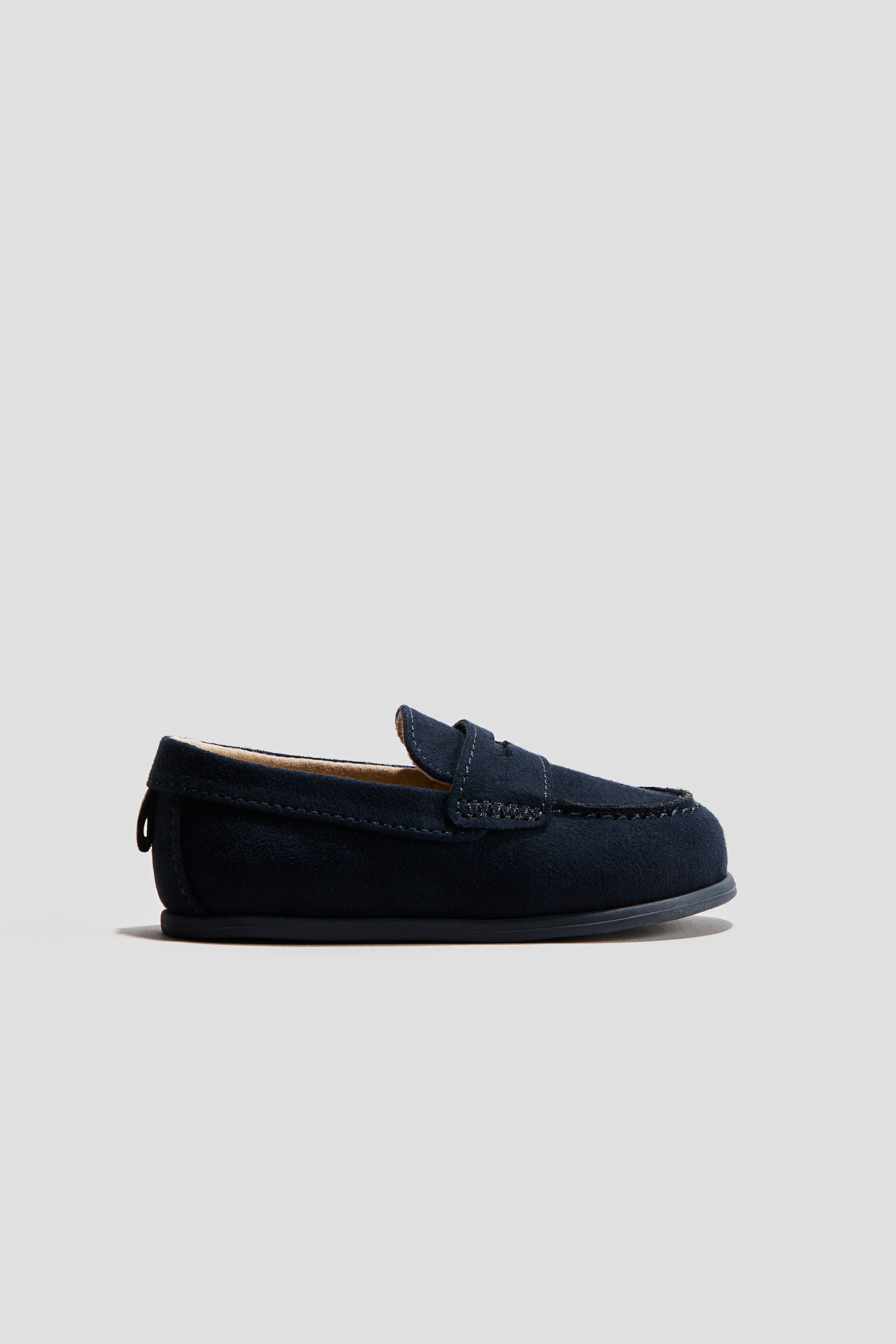 View larger image: Dark blue loafers in napped fabric feature a penny strap across the vamp and a moccasin seam outlining the front. A small loop is visible at the back heel.