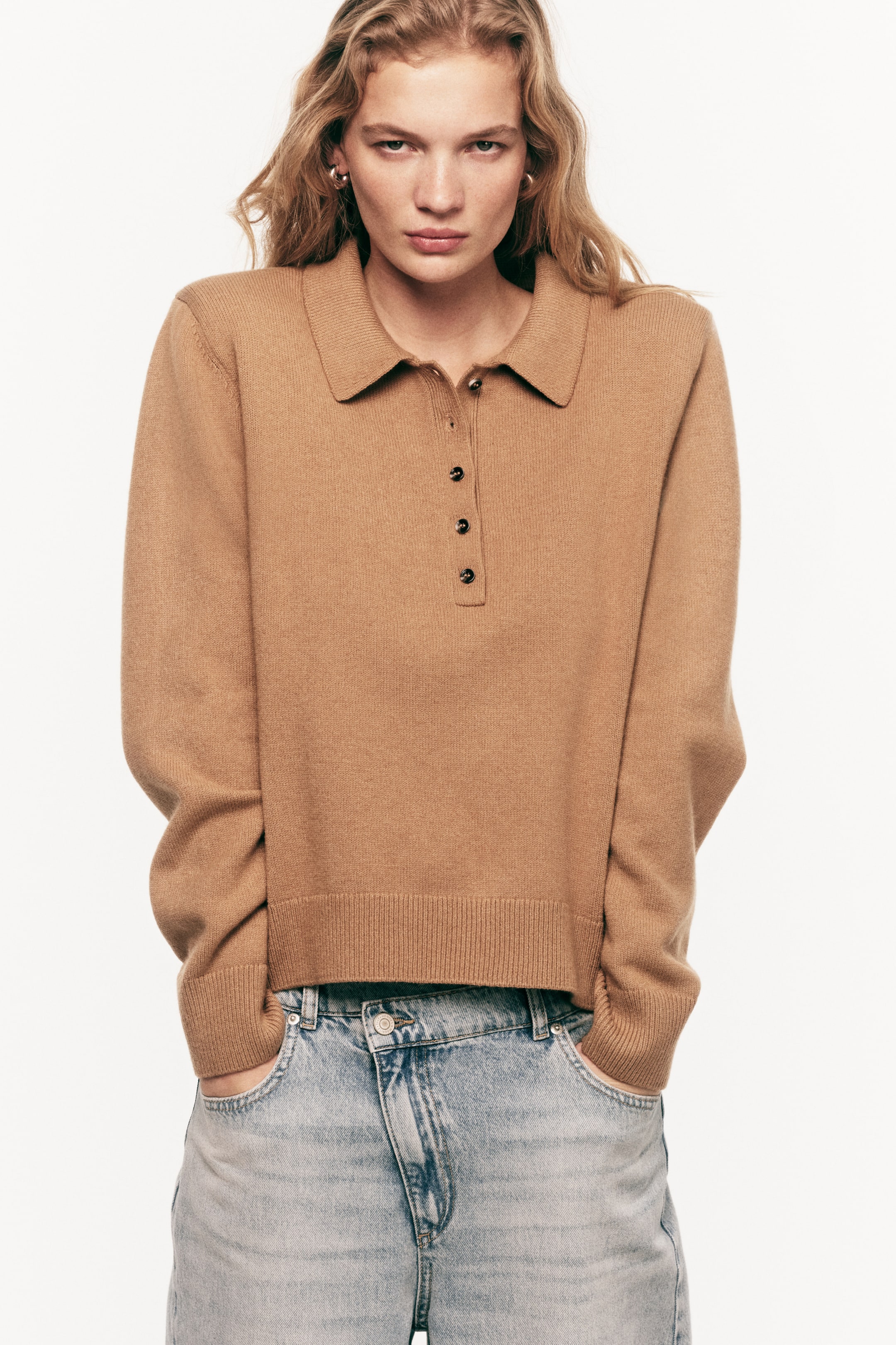 View larger image: A camel-colored knit polo sweater is shown facing forward, with a classic collar, a three-button placket with dark buttons, and a ribbed hem.