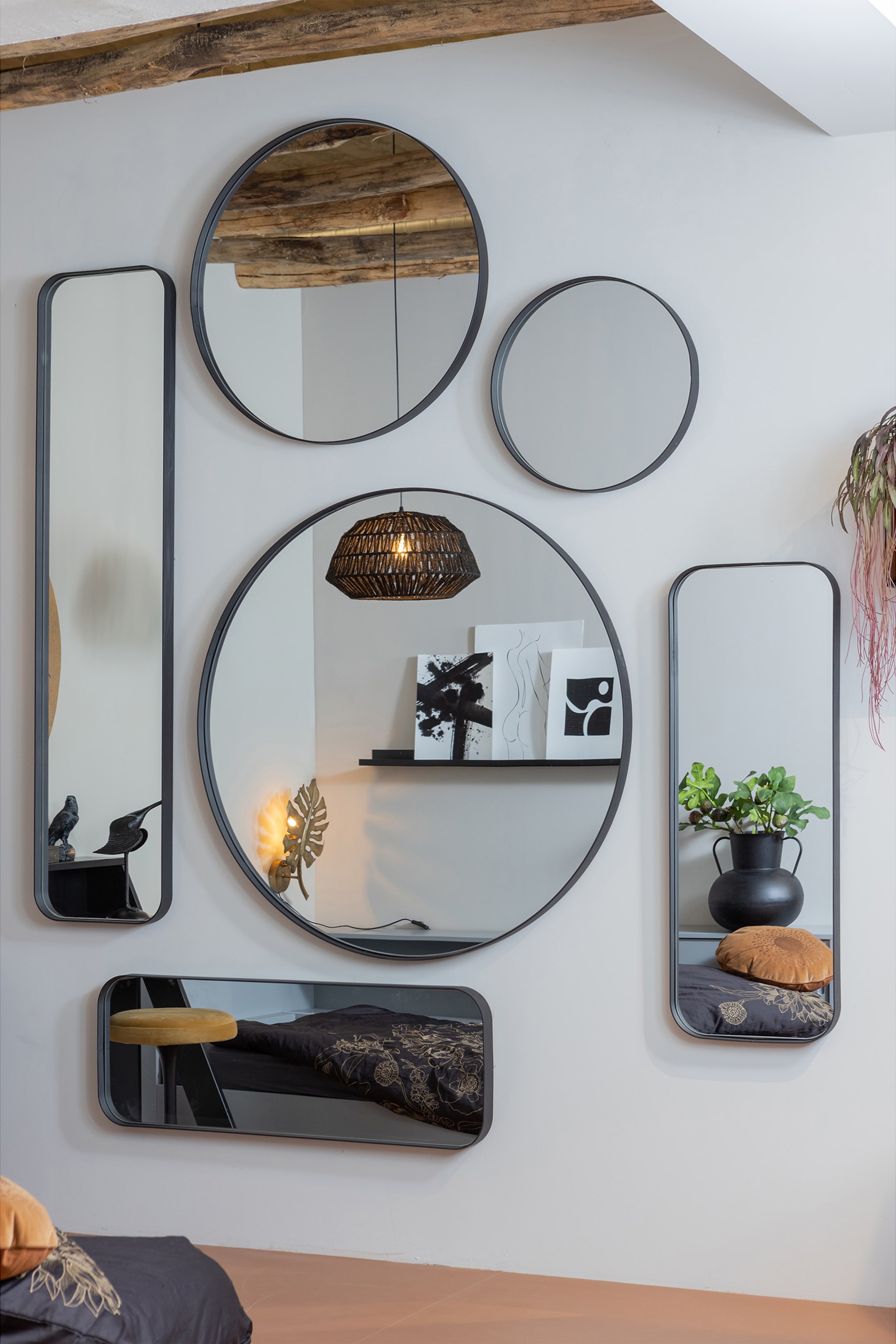 Agrandir l'image: Une collection de miroirs est exposée sur un mur. Elle comprend deux grands miroirs circulaires, un miroir circulaire plus petit, deux grands miroirs rectangulaires avec des coins arrondis, et un petit miroir rectangulaire horizontal avec des coins arrondis. Tous les miroirs sont dotés de cadres fins noirs.