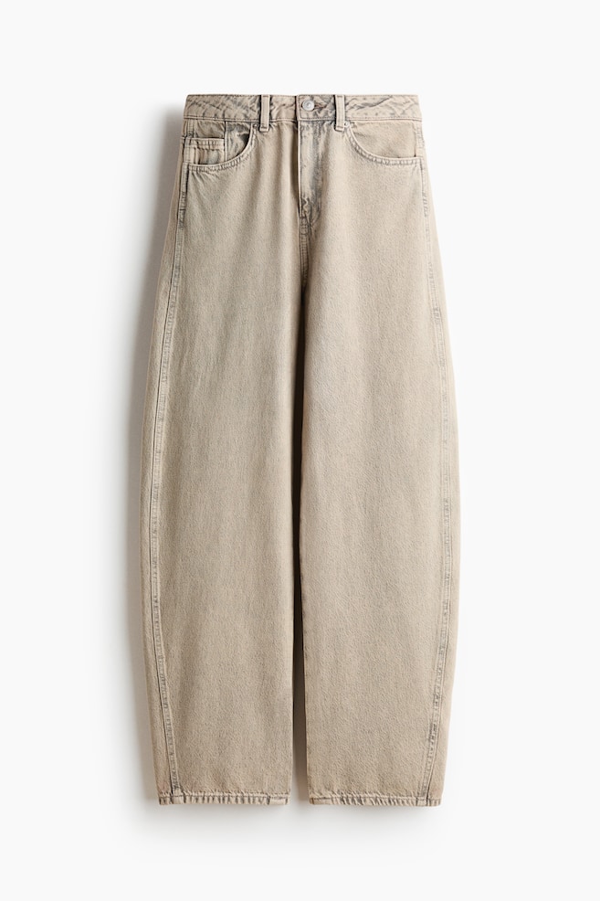 These light beige, acid-washed jeans are presenting a high-waisted, wide-leg silhouette from the front. They are featuring front scoop pockets, belt loops, a button and zipper closure, and slightly frayed hems. - 1