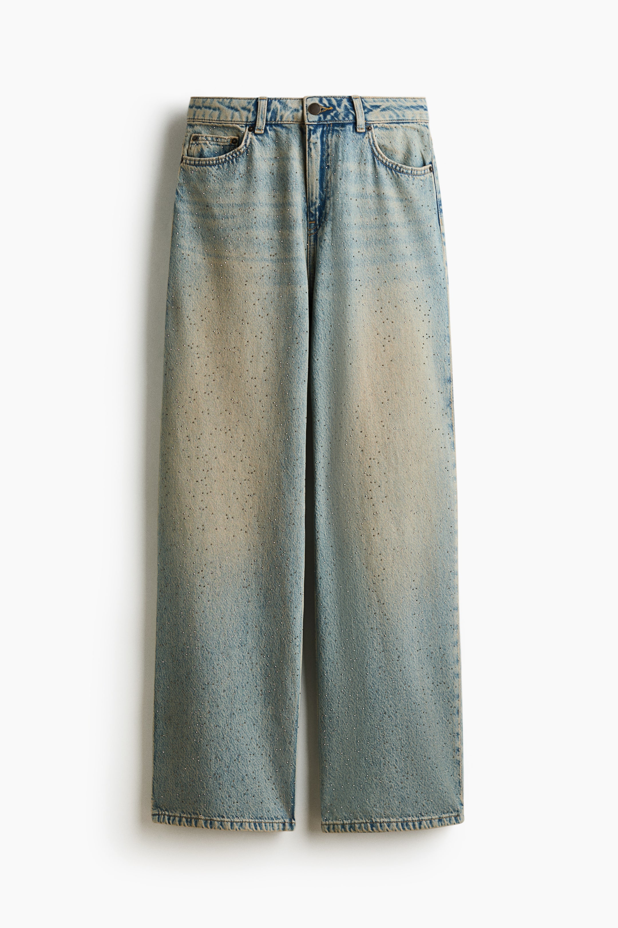 View larger image: A pair of light-wash, straight-leg denim jeans is hanging in a front-facing view, showing a regular waist, five-pocket styling, and a sandy-colored fade down the center of the legs. The jeans feature an all-over scattering of tiny, sparkling rhinestone embellishments.