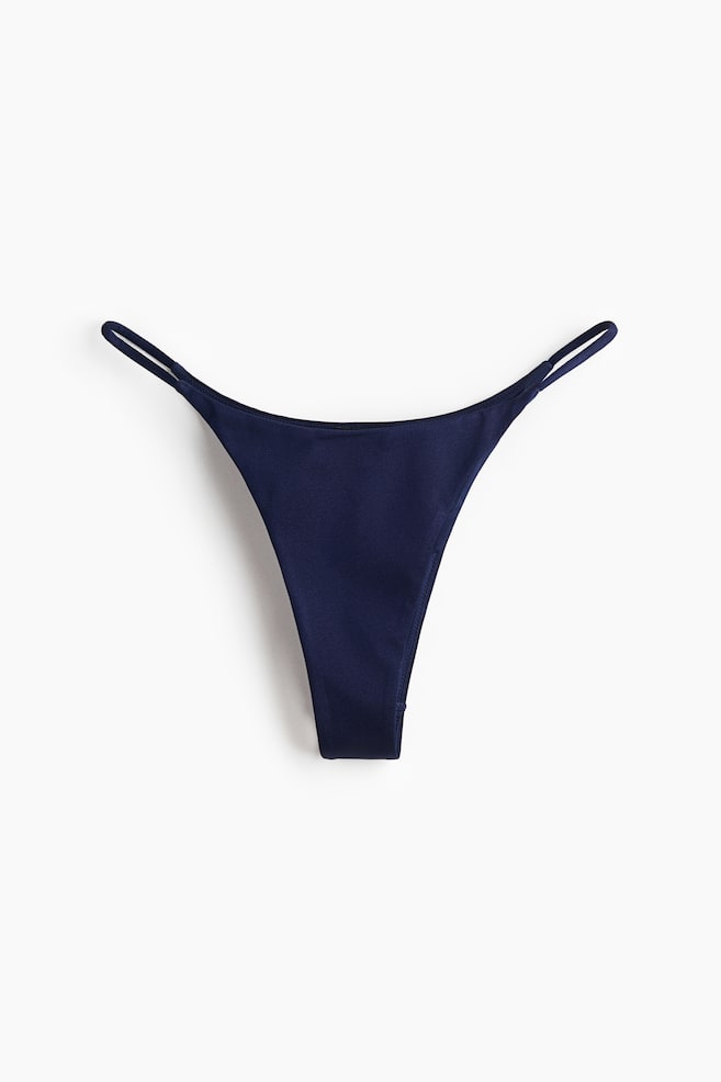 A navy blue thong is presenting its front, featuring thin side straps and a smooth, slightly lustrous fabric. - 1