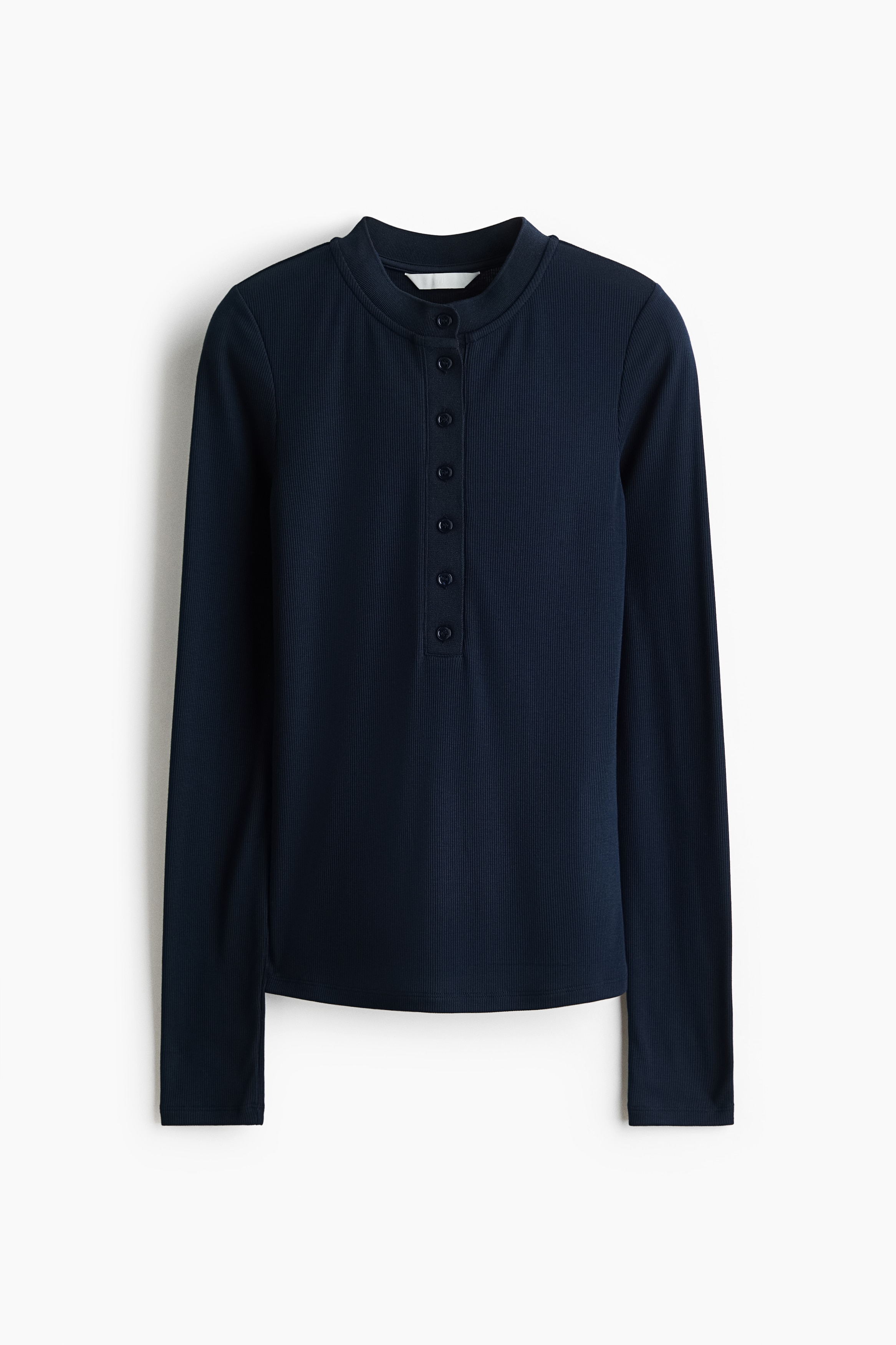 The model is wearing a fitted top in dark navy ribbed jersey, featuring a round neckline with a button placket and long sleeves. The top is styled with a dark denim skirt.