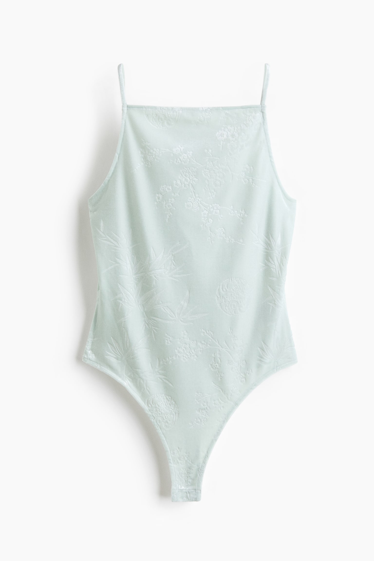 Má»t bá» bodysuit mÃ u xanh báº¡c hÃ  nháº¡t ÄÆ°á»£c chá»¥p tá»« phÃ­a trÆ°á»c, ná»i báº­t vá»i cá» vuÃ´ng vÃ  dÃ¢y vai máº£nh kiá»u spaghetti. Cháº¥t váº£i thá» hiá»n há»a tiáº¿t jacquard tÃ´ng xuyá»t tÃ´ng tinh táº¿ vá»i thiáº¿t káº¿ hoa vÃ  lÃ¡ tre, Ã´m dáº§n xuá»ng pháº§n cáº¯t cao á» á»ng chÃ¢n.
