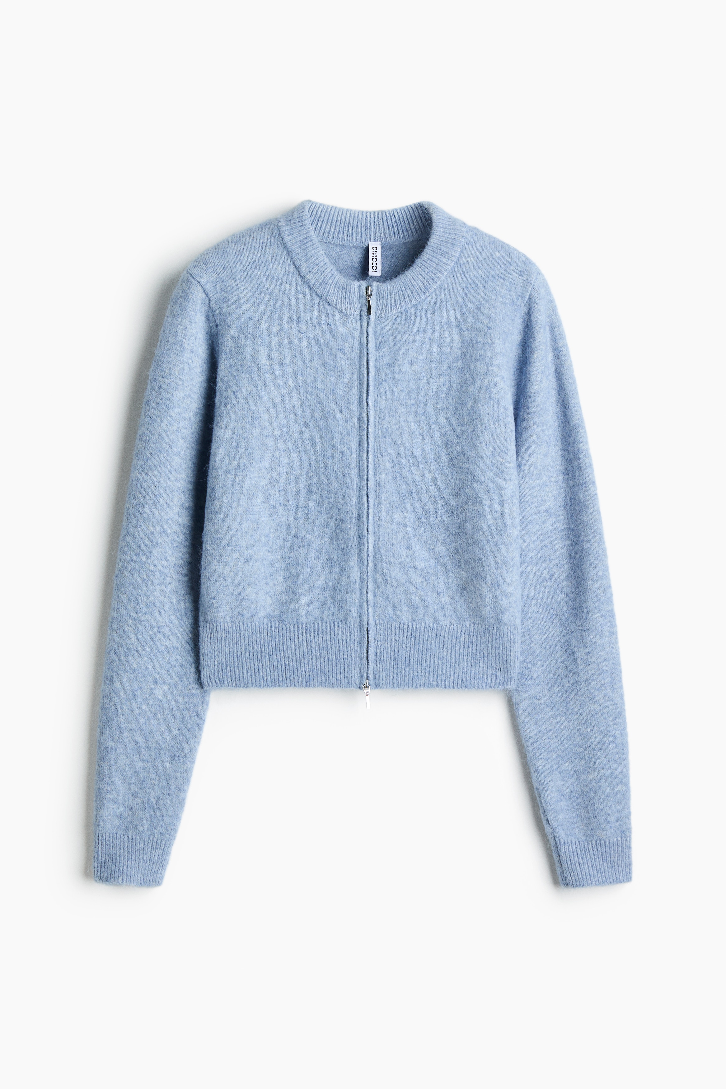 A light blue, soft-knit cardigan featuring a round ribbed neckline, a two-way front zipper, and ribbed cuffs is being worn by the model. The model is adjusting the zipper at the collar with both hands, leaving the bottom of the cardigan partially unzipped.