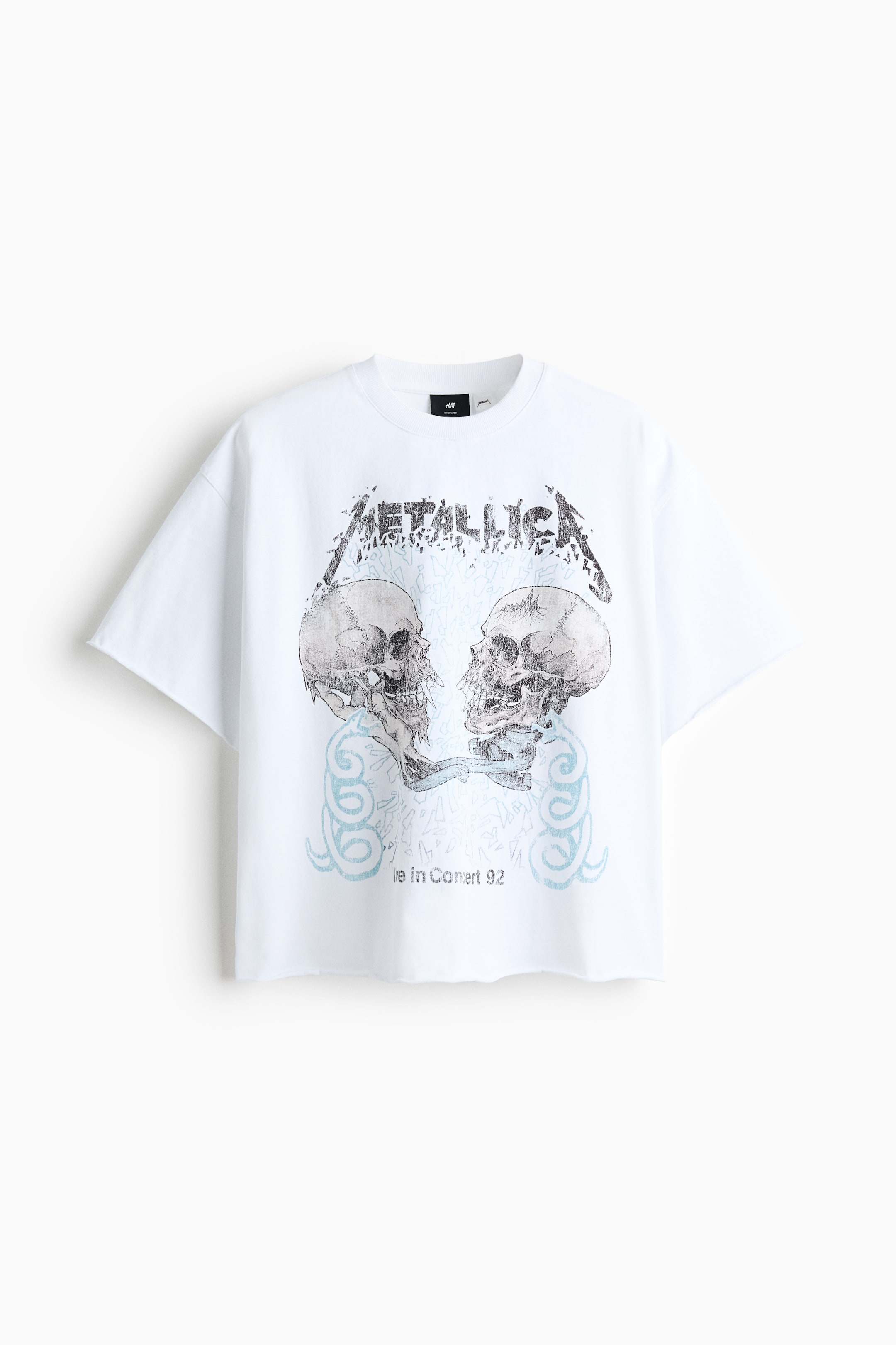 Ver imagen más grande: La camiseta blanca de gran tamaño se presenta en vista frontal, con un estampado gráfico de aspecto desgastado en el pecho que muestra "METALLICA" y dos calaveras. Está diseñada con un cuello redondo con borde de canalé, hombros caídos y sisas y dobladillo con borde enrollado y sin rematar.