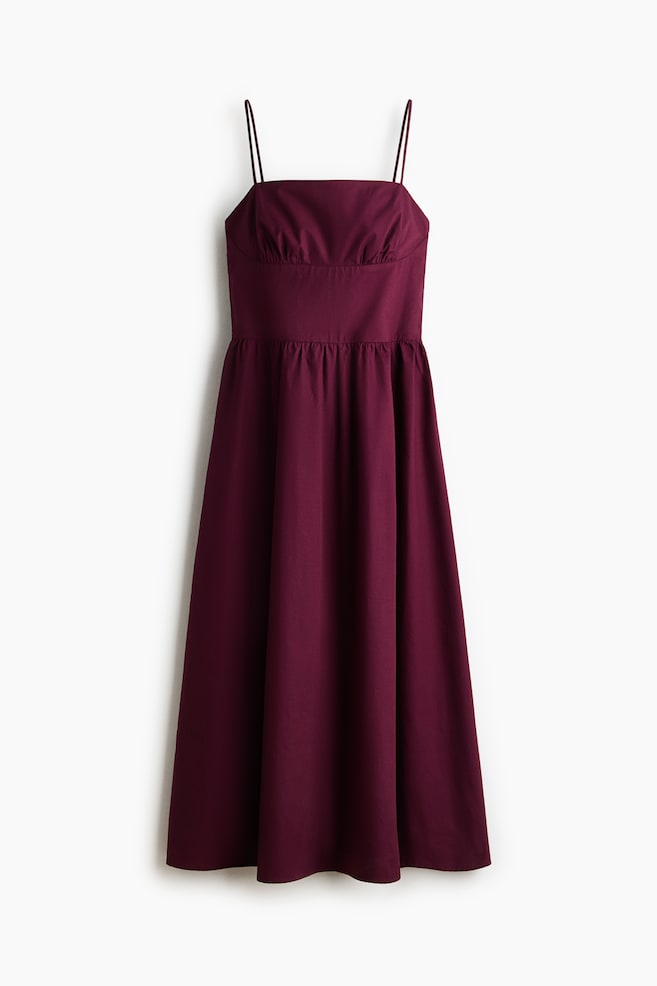 A burgundy midi dress is featuring a straight neckline with thin spaghetti straps, and a fitted bodice displaying horizontal ruching across the bust. The gathered waistline is leading to an A-line skirt. - 1