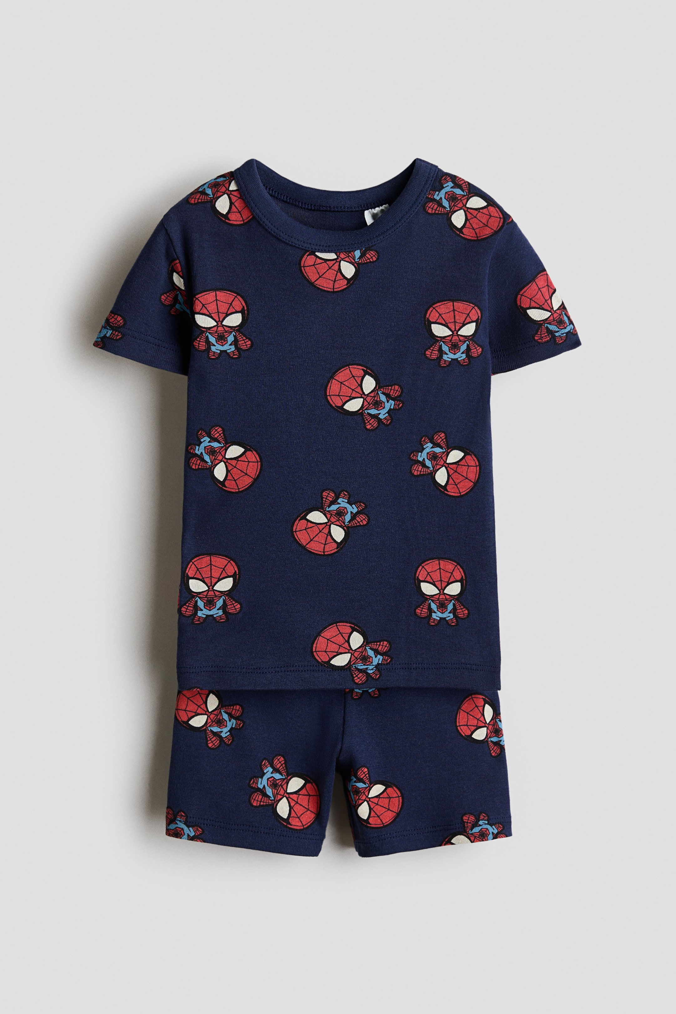 View larger image: The pajama T-shirt and shorts set is shown from the front. The navy-blue set features a repeating print of red and blue Spider-Man characters and masks. The T-shirt has short sleeves and a round neckline, while the shorts have an elastic waistband.