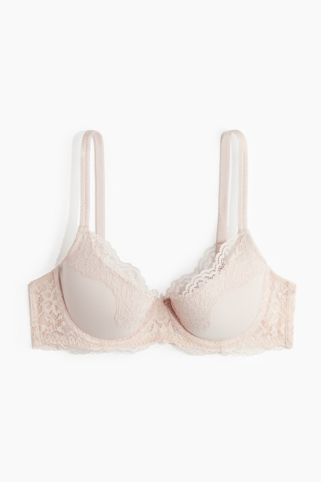 Un sutien bej deschis este prezentat din față, având cupe netede și modelate, cu o dantelă florală delicată care acoperă marginile superioare și se extinde de-a lungul benzii. Acesta prezintă bretele subțiri și o margine de dantelă ondulată de-a lungul părții de jos. - 1