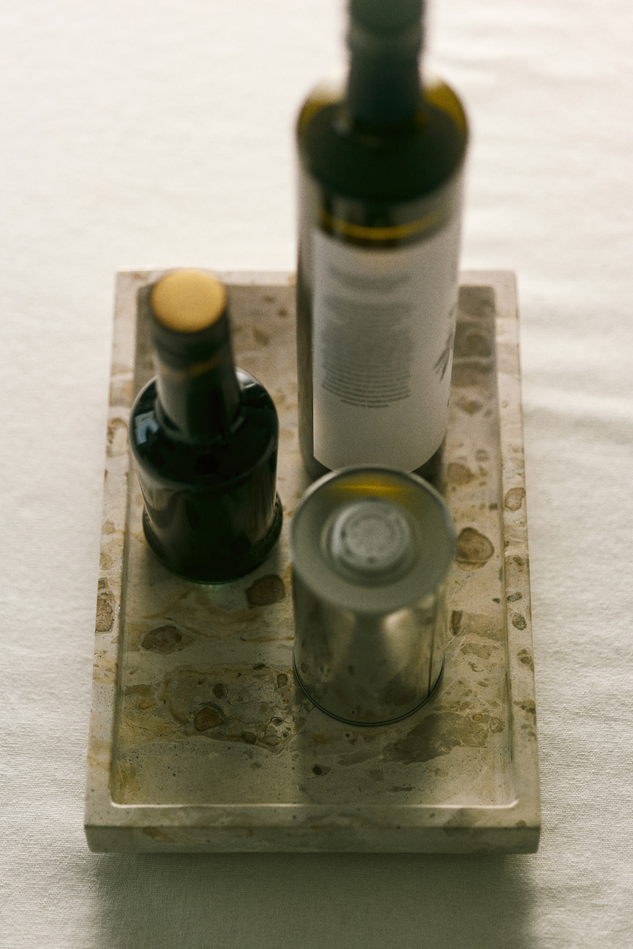 View larger image: The rectangular tray is being viewed from a top-down angle, showcasing its shallow, raised edges and mottled stone surface, while it is holding two bottles and a metal can.