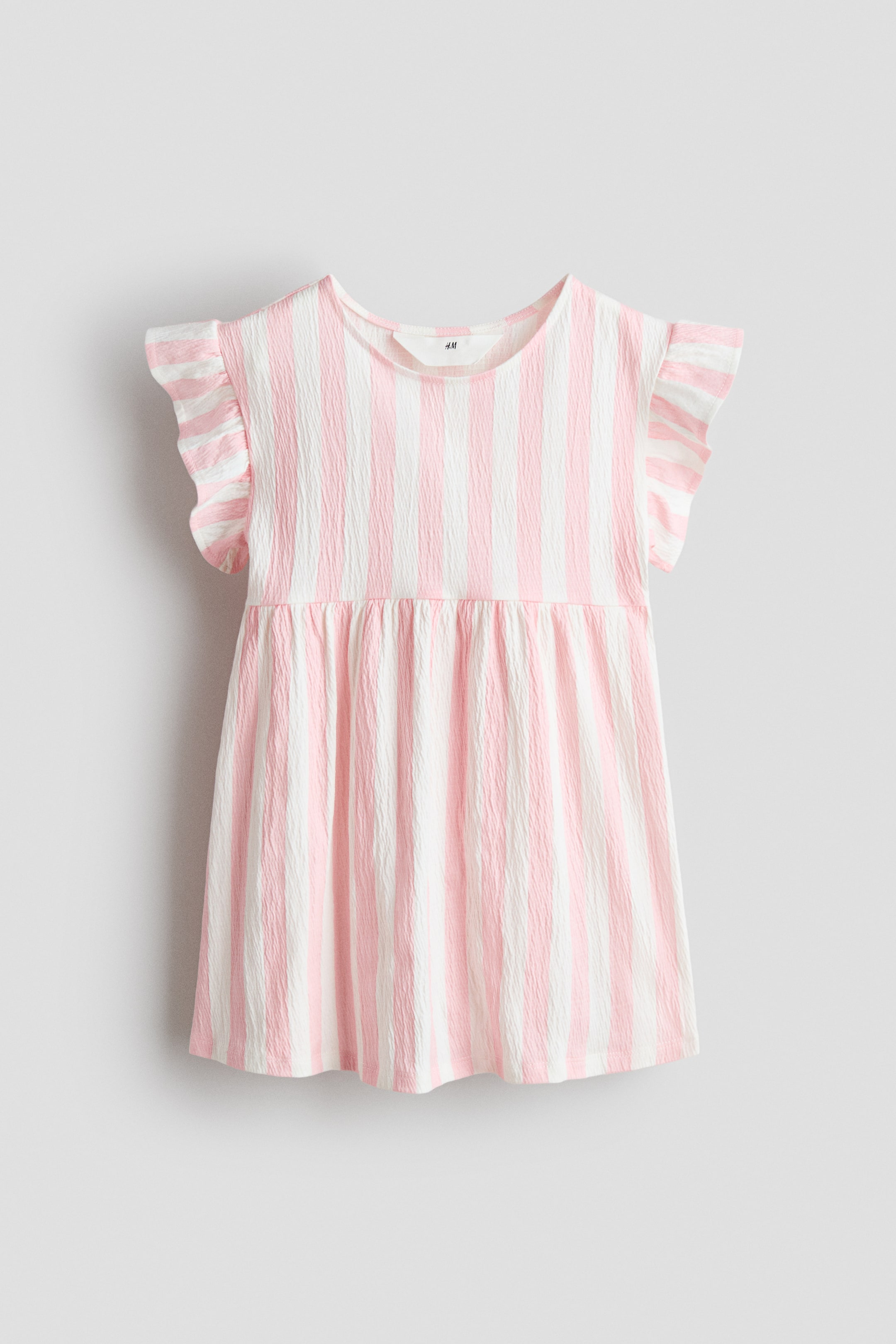 Büyük resmi görüntüle: Önü açık bir elbise, dikey pembe ve beyaz çizgilerle sergileniyor. Yuvarlak bir yaka, kısa fırfırlı kollar ve belde toplanmış bir dikişle rahat bir A-kesim eteğe dönüşen buruşuk bir dokuya sahip.