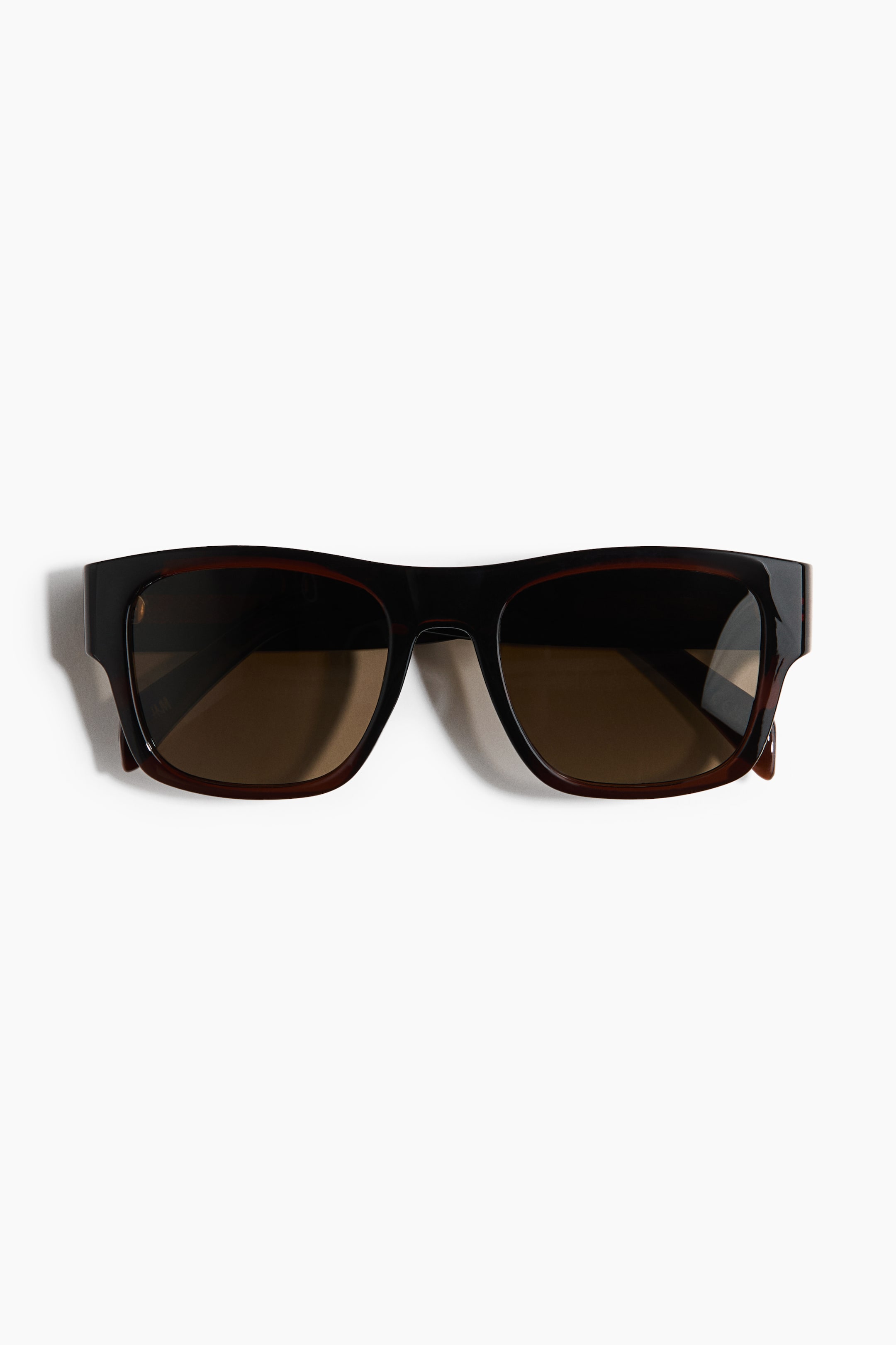 Agrandir l'image: Lunettes de soleil en plastique marron foncé orientées vers l'avant, avec des montures rectangulaires épaisses arborant un motif écaille discret et des verres teintés marron foncé.