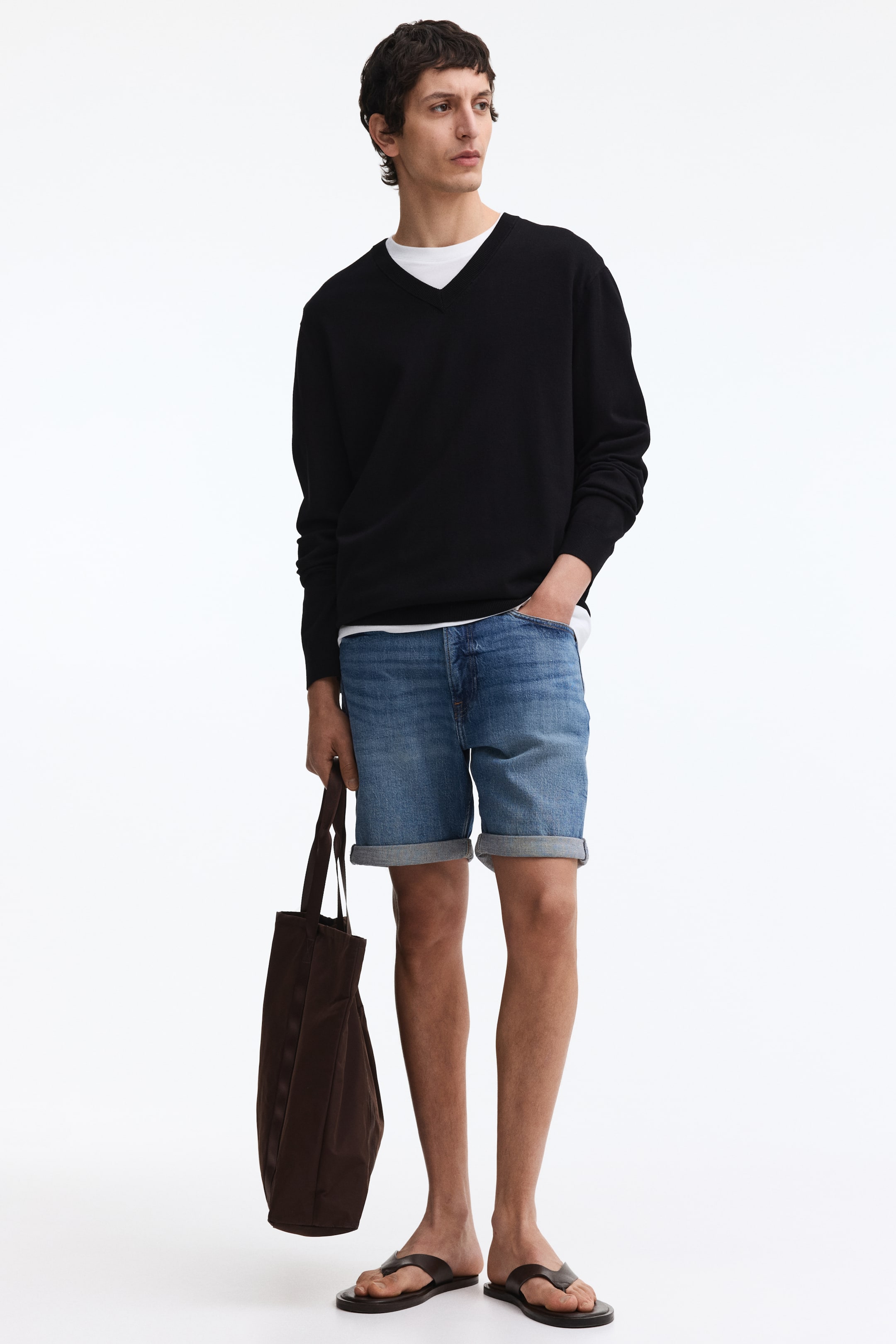 View larger image: A black V-neck sweater is worn, featuring a V-neckline, long sleeves, and a relaxed fit. A white crew neck t-shirt is layered underneath, visible at the neckline and hem.