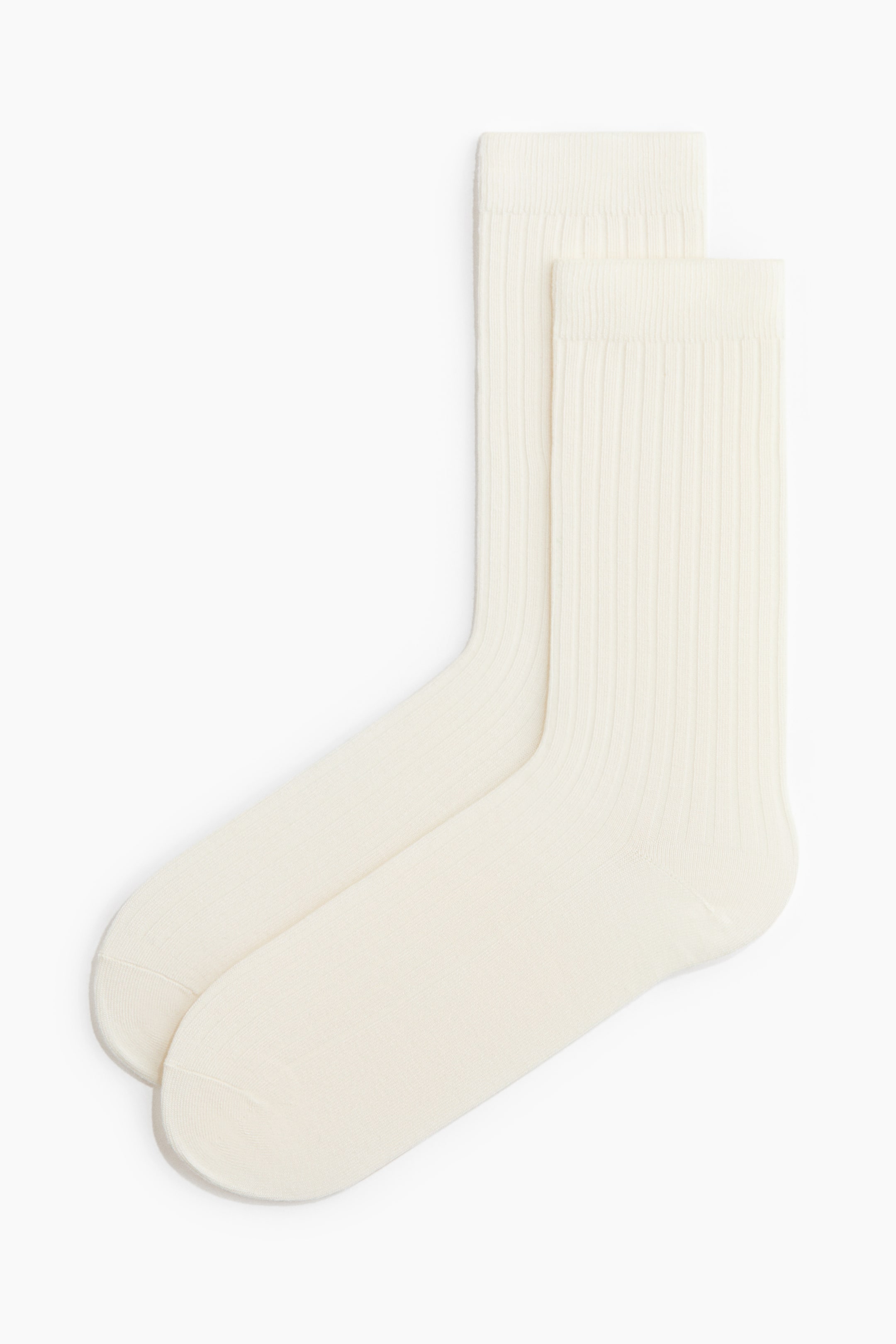 View larger image: Ribbed socks are lying flat, slightly overlapping, showcasing their cream colour, fine-knit texture, and wide elasticated tops.