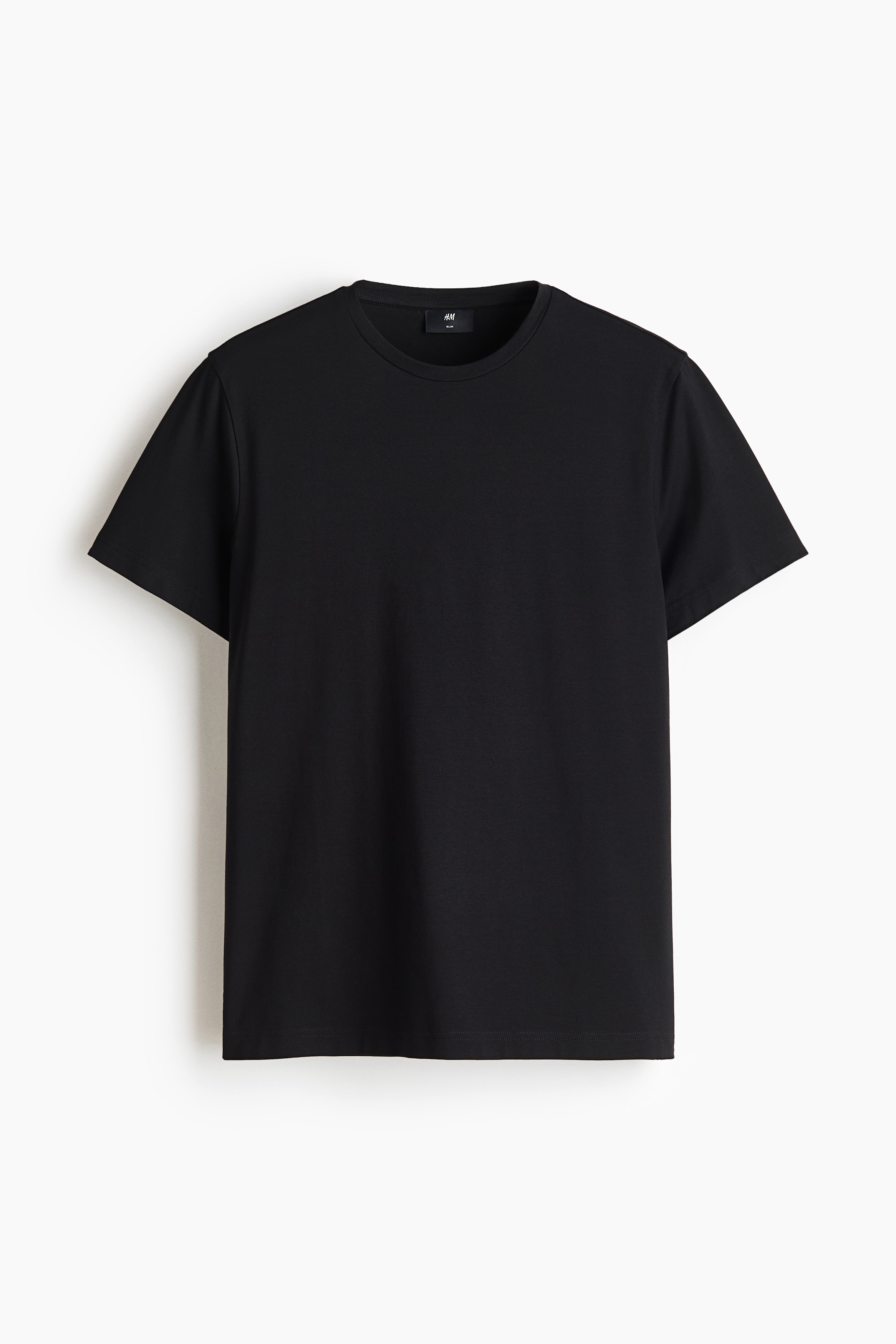 The model is wearing a black, short-sleeved crew-neck T-shirt. The classic-fit T-shirt is styled with light-wash blue jeans, with the modelâs hands resting in the front pockets.