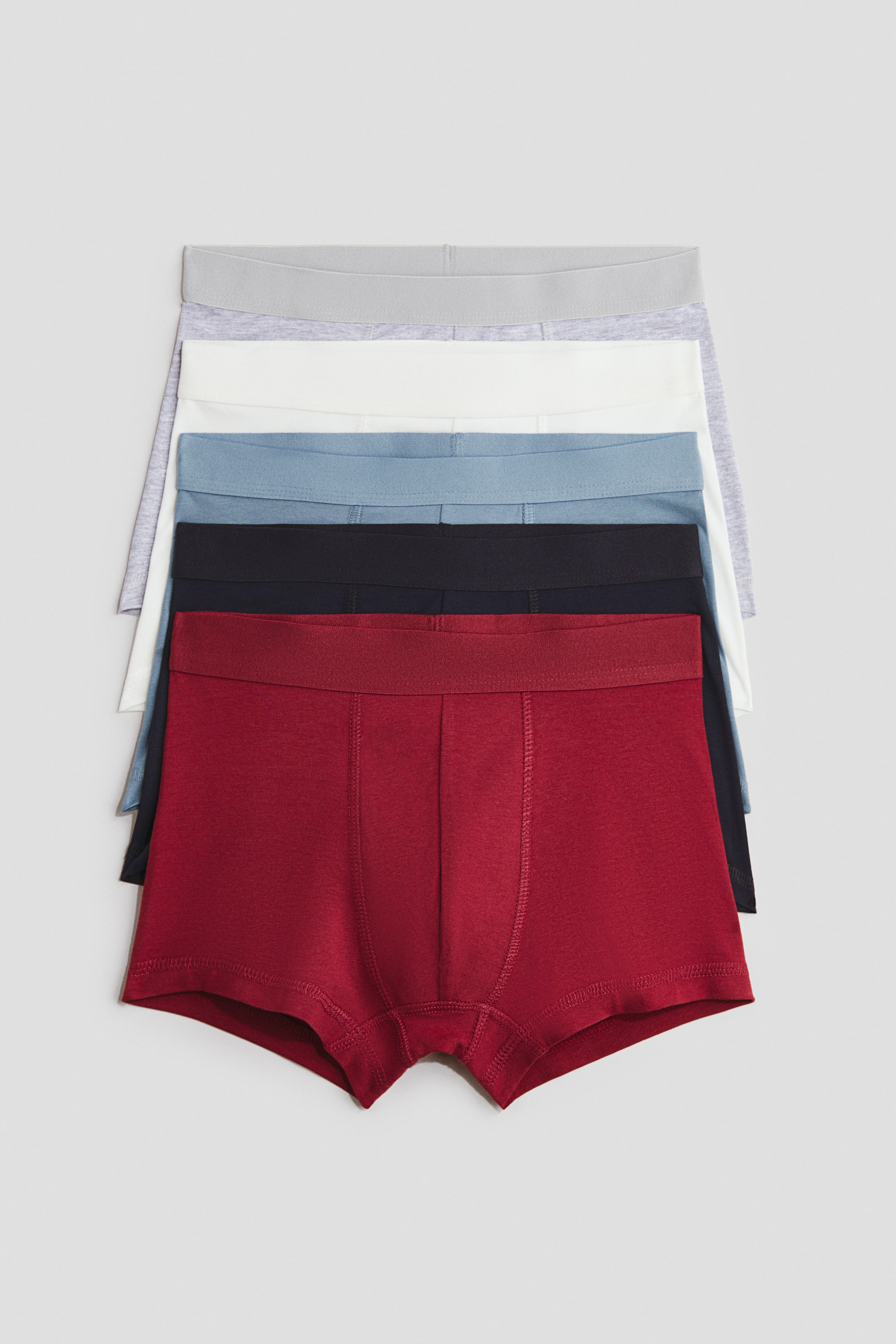 View larger image: Trunks in cotton jersey with short legs, an elasticated waist, and a lined front are presented in a stack. The stack is displaying multiple colours including red, black, light blue, white, and light grey, with the bottom red trunk facing front.