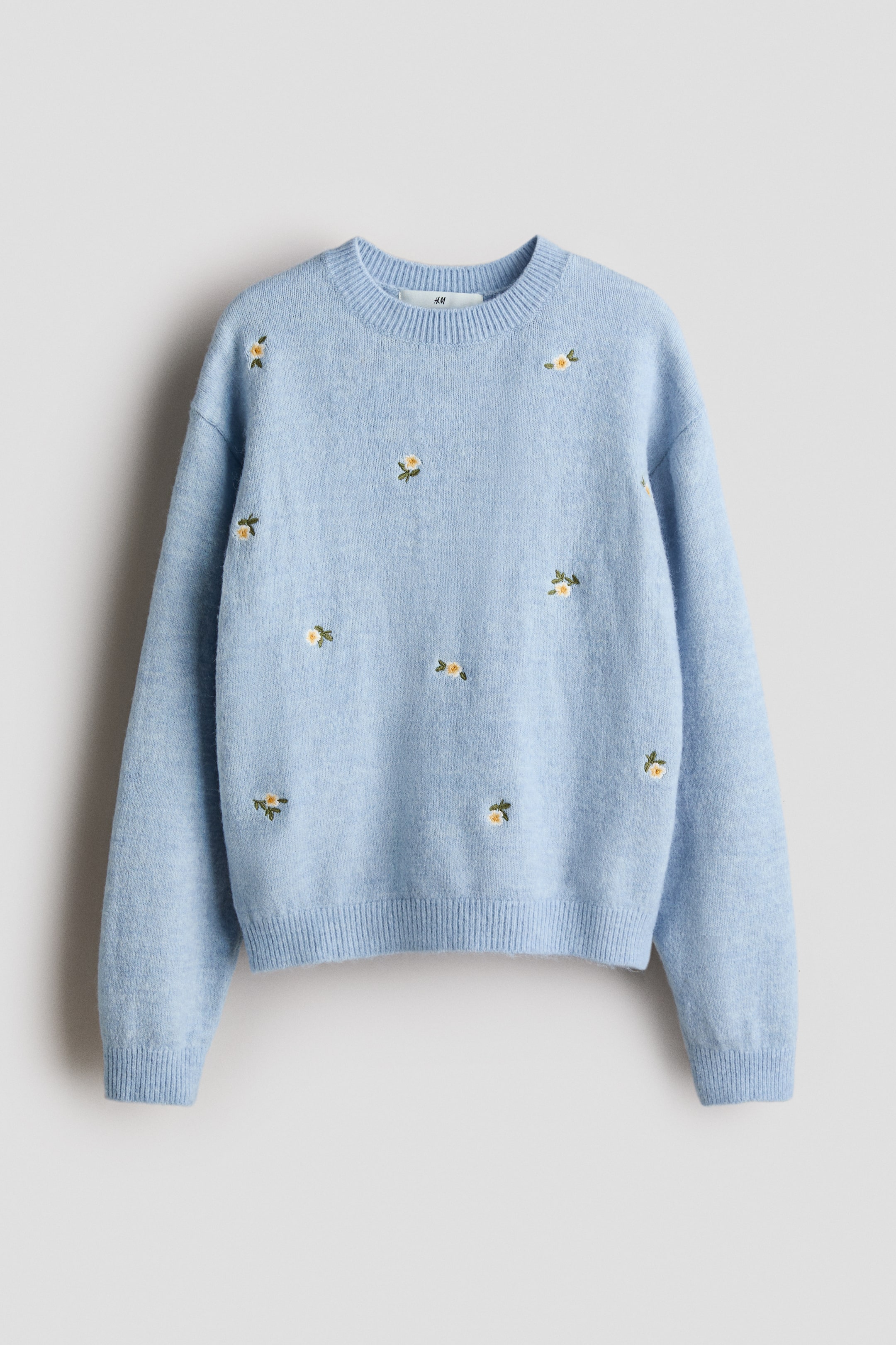 View larger image: A light blue jumper is being shown from the FRONT, made of a soft, fine knit. It features a round, rib-trimmed neckline, dropped shoulders, and ribbed cuffs and hem, with small embroidered white and yellow flowers scattered across its surface.