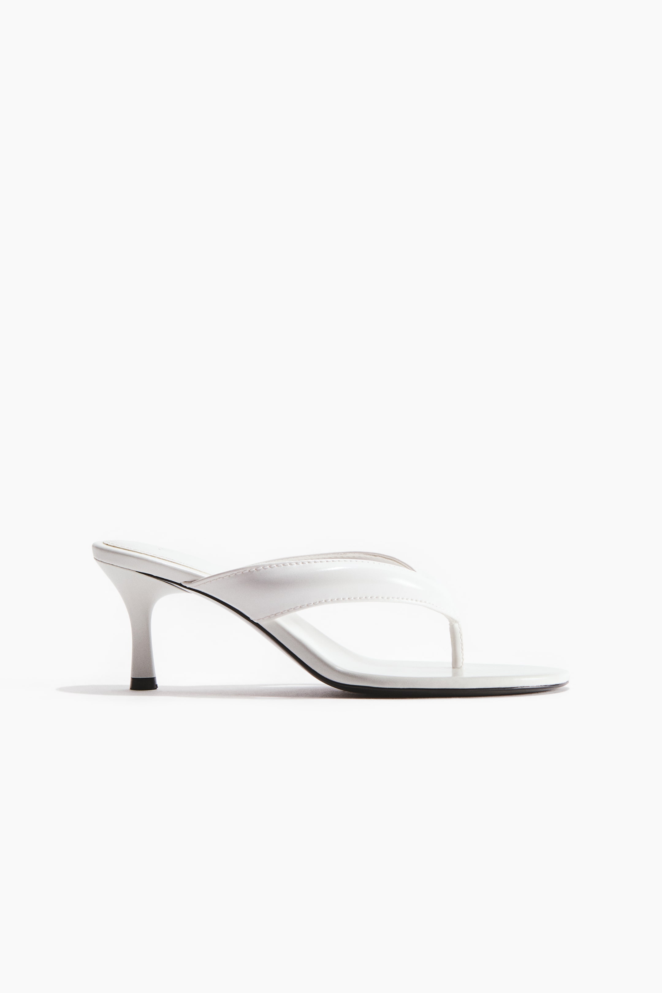View larger image: A white high-heeled thong sandal is positioned sideways. It showcases a glossy V-shaped upper with a toe post, a slim flared heel, and a black outsole.