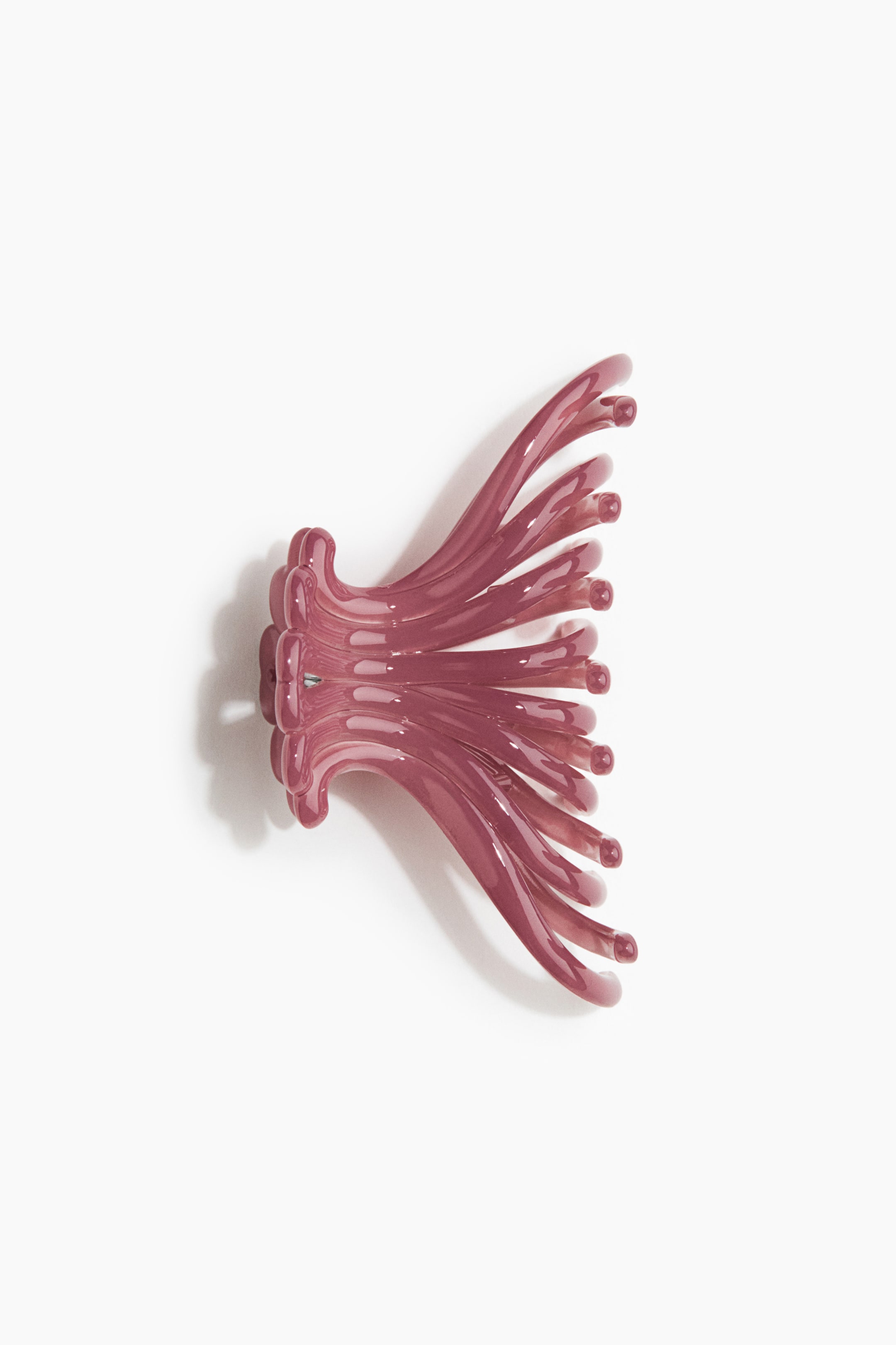 View larger image: "Glossy plastic hair claw. The translucent, dusky rose hair claw rests on its side, showcasing its two hinged sections with multiple curved claws extending outwards."