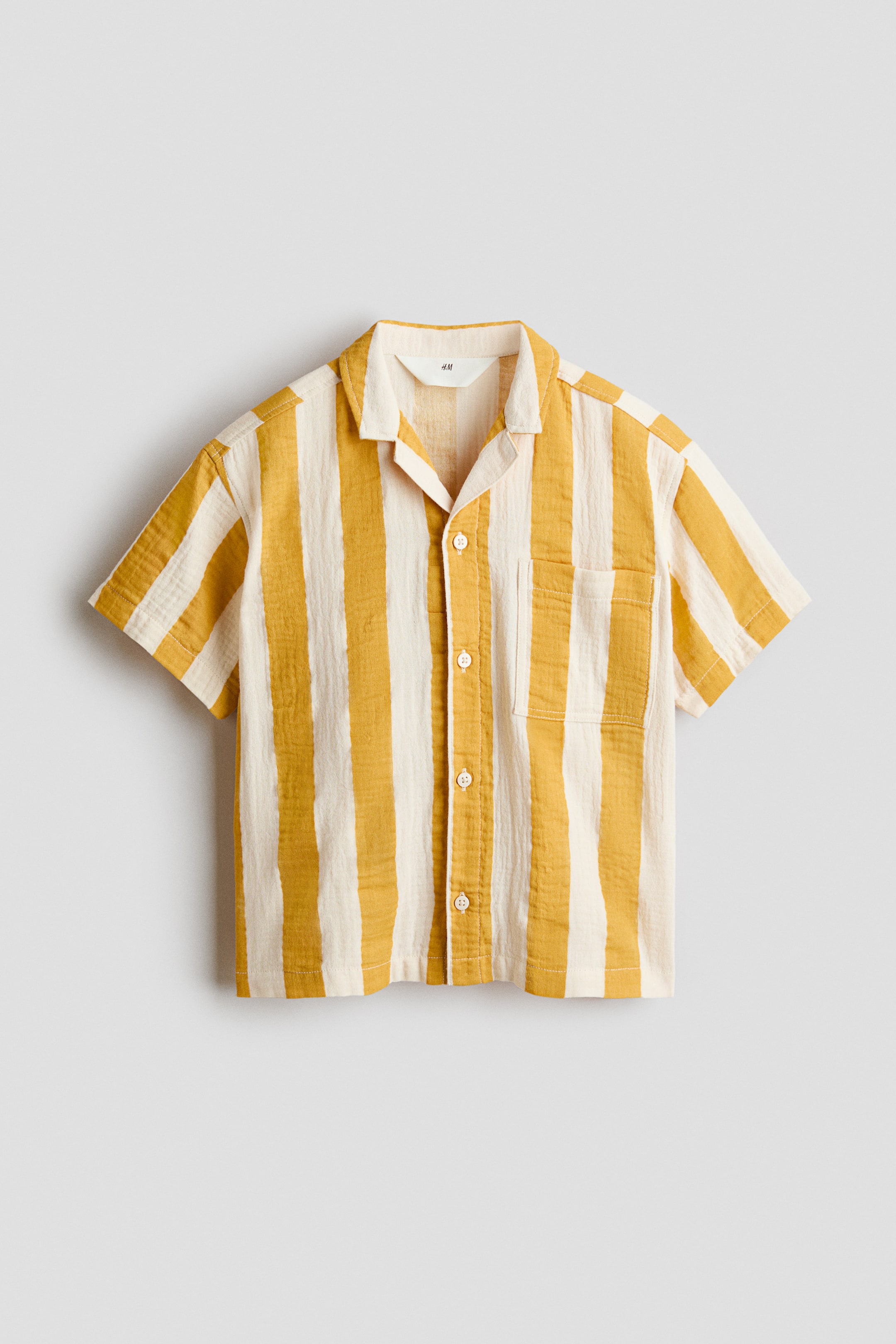 View larger image: "A short-sleeved shirt, FRONT, showcases yellow and off-white vertical stripes on a textured fabric. It is crafted with a camp collar, short sleeves, a button-front closure, and a single chest pocket on the left side."