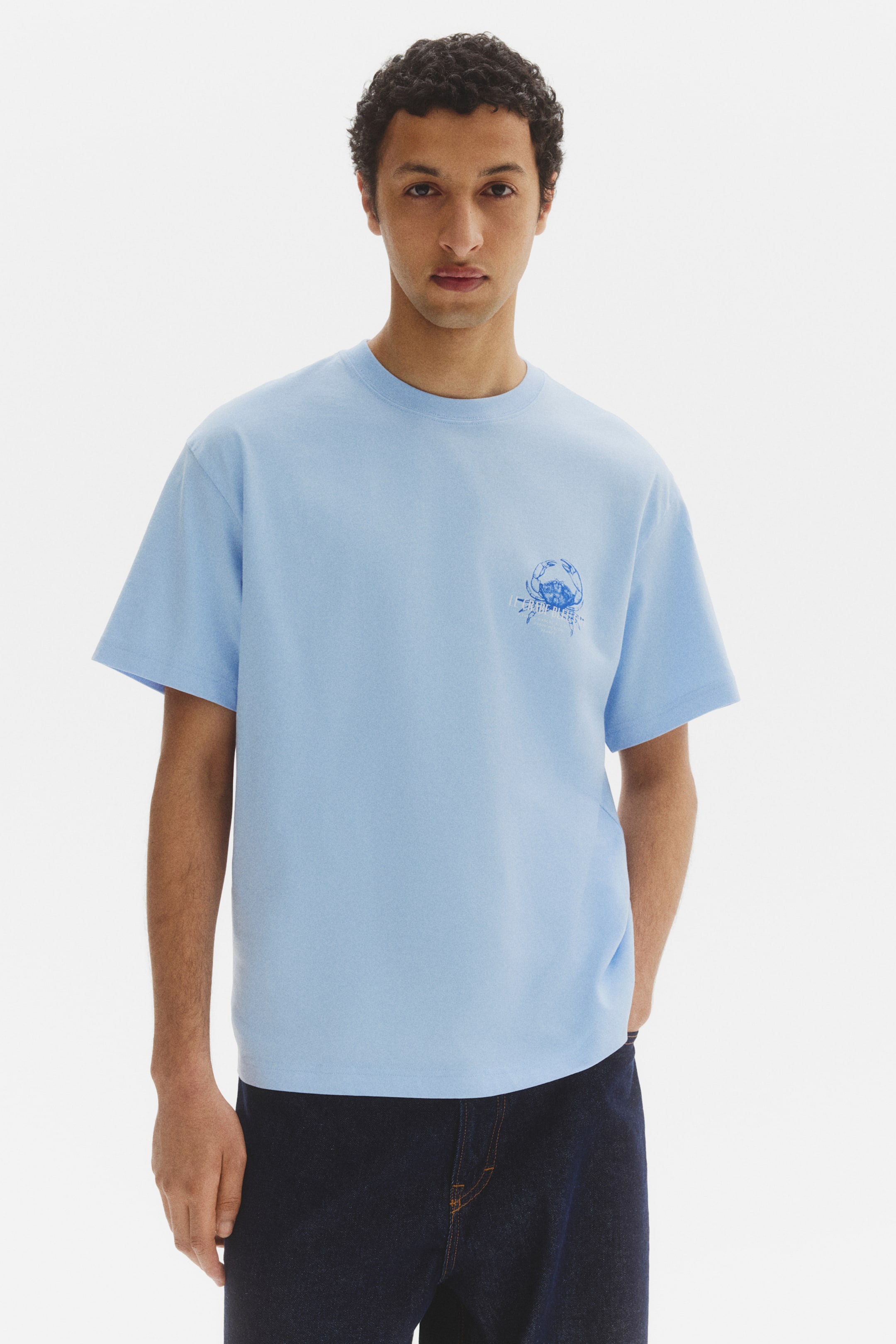 View larger image: The t-shirt in a soothing light blue shade is styled with a relaxed fit, featuring a crew neck and short sleeves, presented front-facing. A blue crab graphic embellishes the left chest.