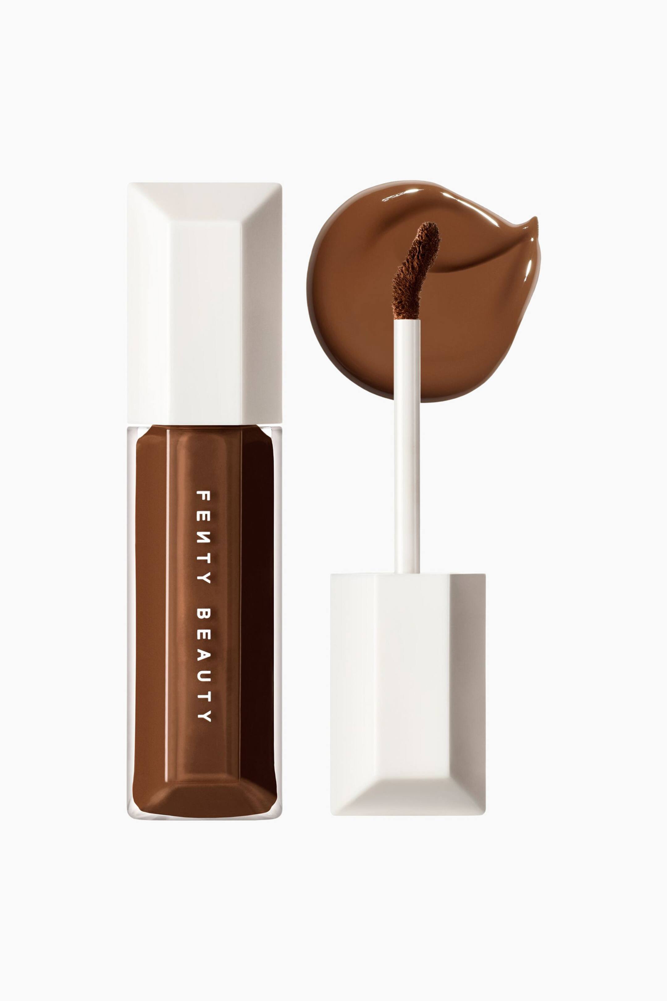 Visa större bild: We're Even Hydrating Longwear Concealer står upprätt bredvid sin öppna applikatorstav och visar en djupbrun nyans genom sin transparenta, rektangulära flaska med ett vitt, facetterat lock. Applikatorstaven, med matchande vitt lock och skaft, håller en brun doe-foot-spets framför ett cirkelformat, slätt prov av den djupbruna flytande concealern.