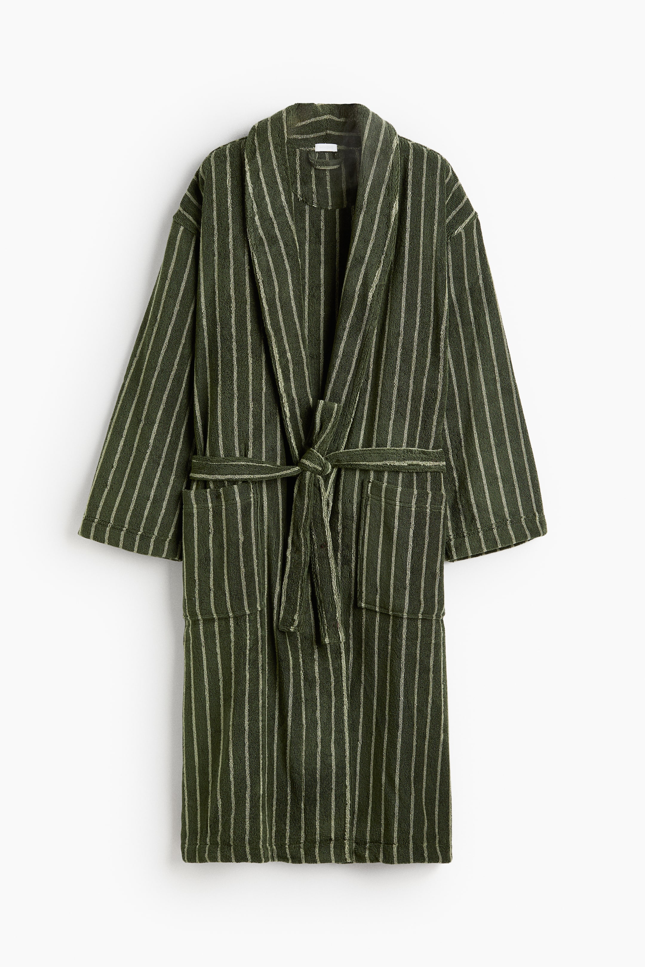 View larger image: A dark olive green cotton terry dressing gown with vertical cream stripes is shown from the front, featuring a shawl collar and long sleeves. The dressing gown displays two front patch pockets and a matching fabric tie belt knotted at the waist.