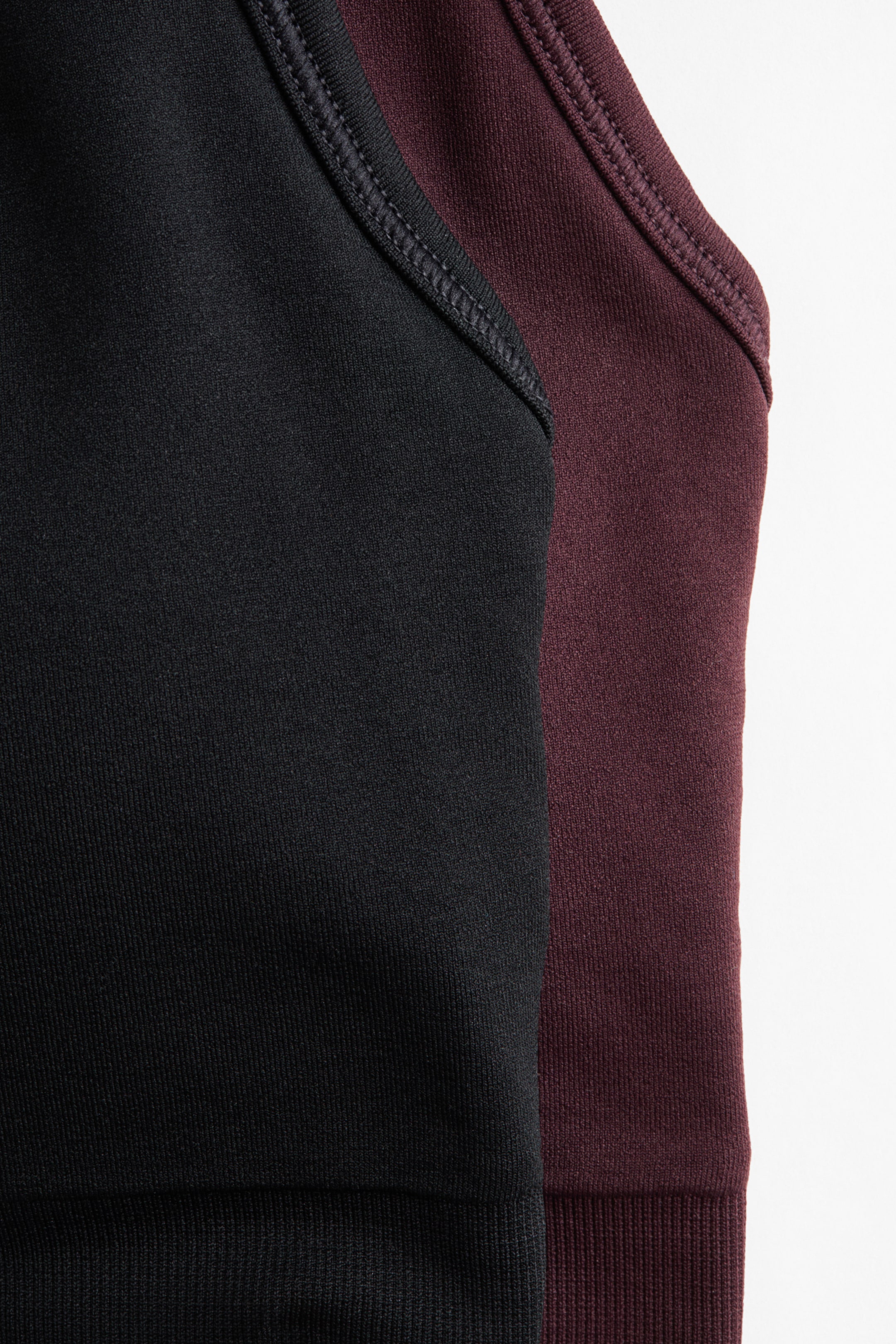 Visualizza l'immagine ingrandita: Un set da 2 reggiseni sportivi senza cuciture è visibile, con un reggiseno nero sovrapposto a un reggiseno color bordeaux. Entrambi i reggiseni presentano spalline strette con cuciture visibili e fasce inferiori a coste.