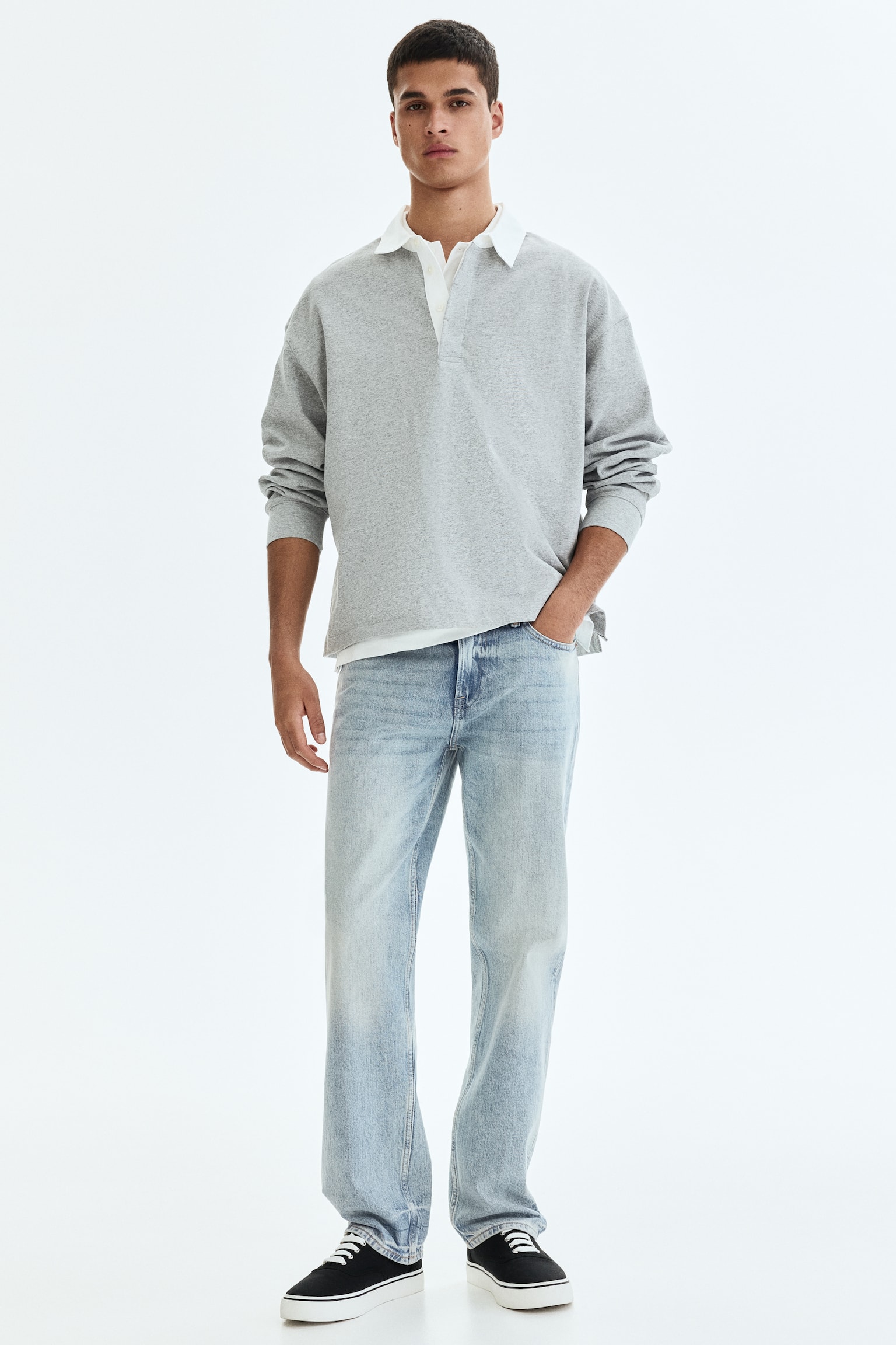 A grey long-sleeve polo shirt is on display from a front perspective, featuring a white collar and a placket. A white undershirt collar is visible underneath, and the polo boasts a relaxed fit with long cuffed sleeves. - 1