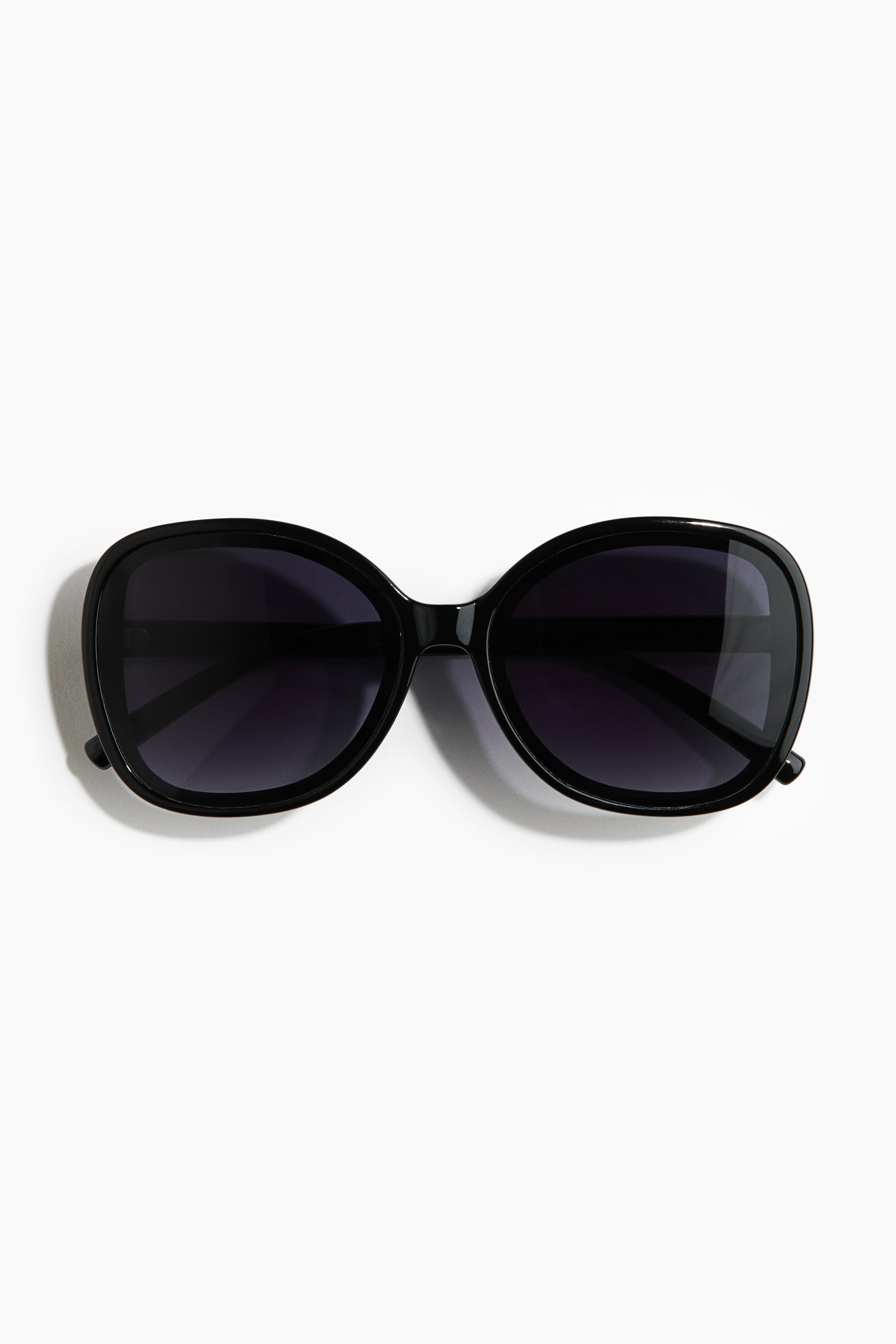 View larger image: The black sunglasses showcase an oversized, glossy black, rounded frame paired with dark, uniformly tinted lenses, presented facing front.