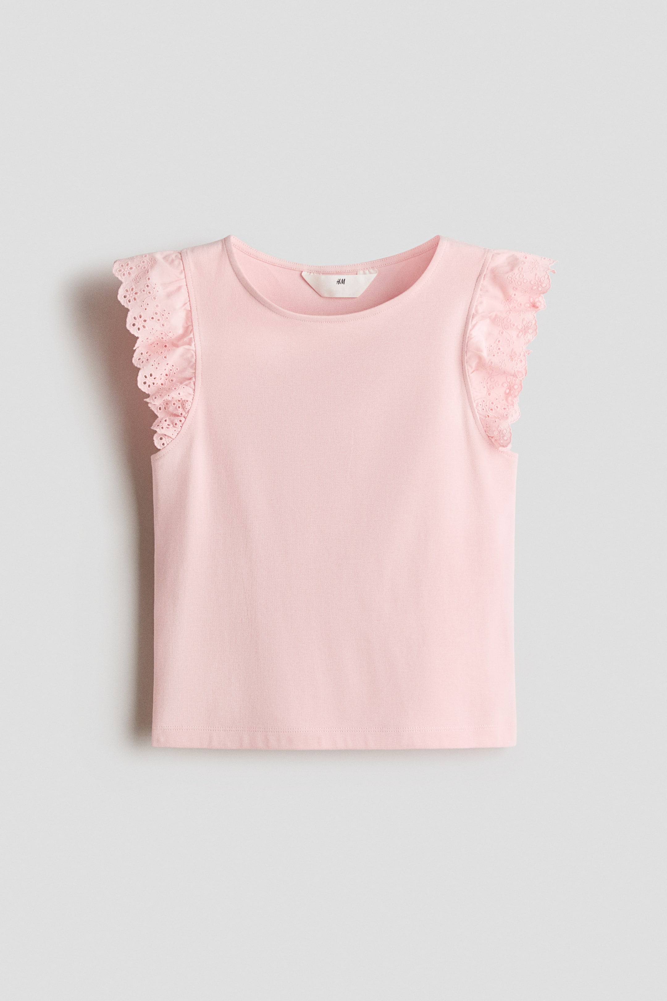 Visualizza l'immagine ingrandita: Un top rosa è presentato frontalmente, realizzato in morbido jersey di cotone e caratterizzato da uno scollo rotondo con maniche a volant in tessuto di cotone, dettagliato con broderie anglaise e bordi smerlati.