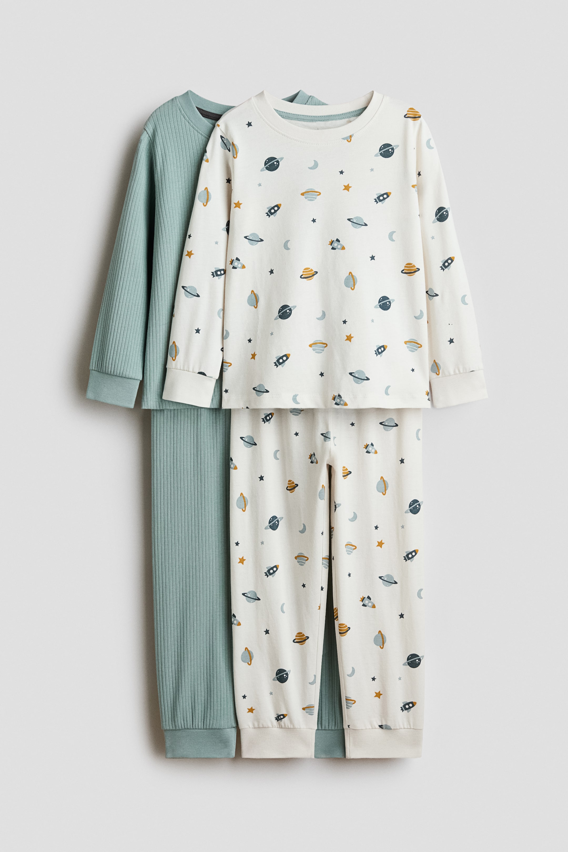 View larger image: A pair of pyjamas, displayed from the front, features a long-sleeved top and matching bottoms in soft, printed cotton jersey with a blue, yellow, and grey space-themed pattern on an off-white background. The top showcases a round, rib-trimmed neckline and ribbed cuffs, while the bottoms boast an elasticated waist and ribbed hems.