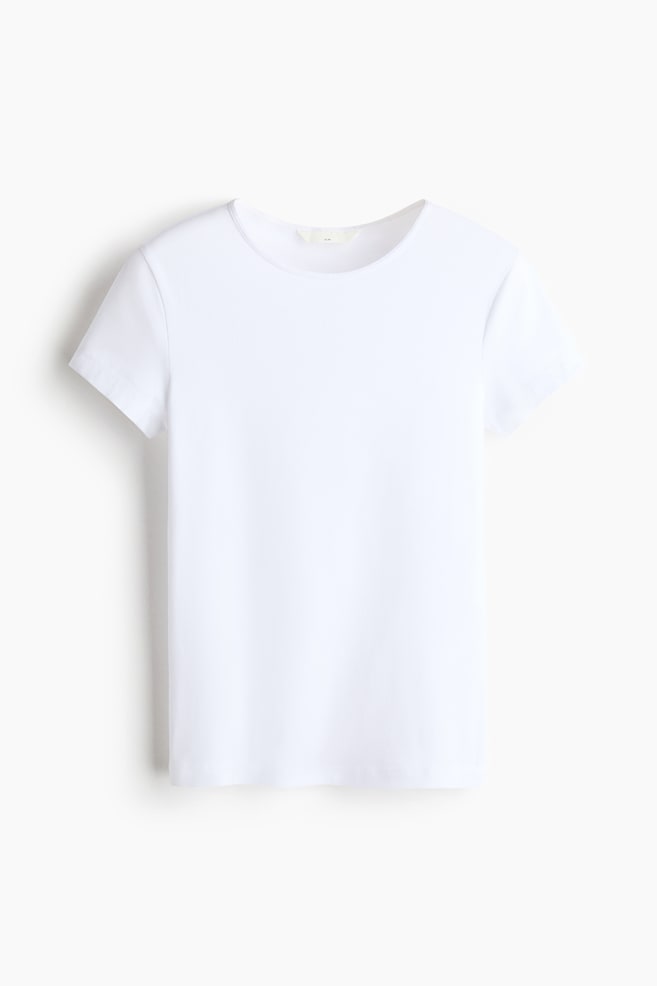 Una T-shirt in jersey di cotone bianco aderente Ã¨ mostrata frontalmente, con scollo tondo, maniche corte e orlo a taglio dritto. - 1