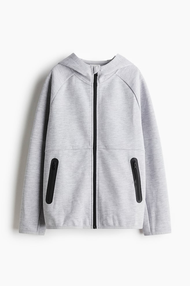 A grey sports hoodie is being presented from the front. A full-length black zipper is running down its center, an attached hood and raglan sleeves are shaping the top, and two black zippered pockets are detailing the lower front. - 1