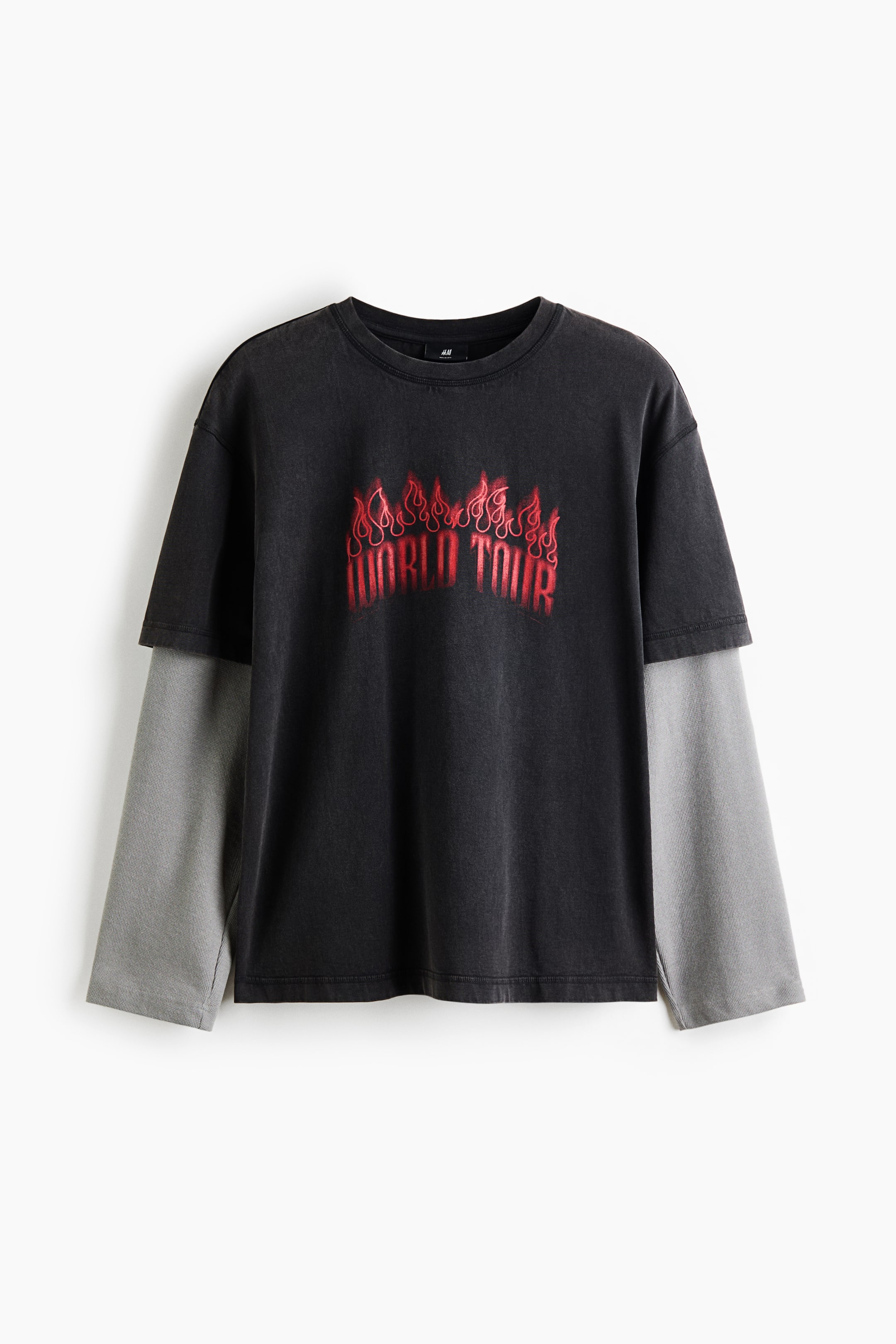 View larger image: This front-facing, relaxed-fit T-shirt in washed dark grey cotton jersey features a red "WORLD TOUR" graphic with flames printed across the chest. The design showcases a ribbed round neckline, dropped shoulders, a straight hem, and short sleeves layered over contrasting light grey long sleeves.